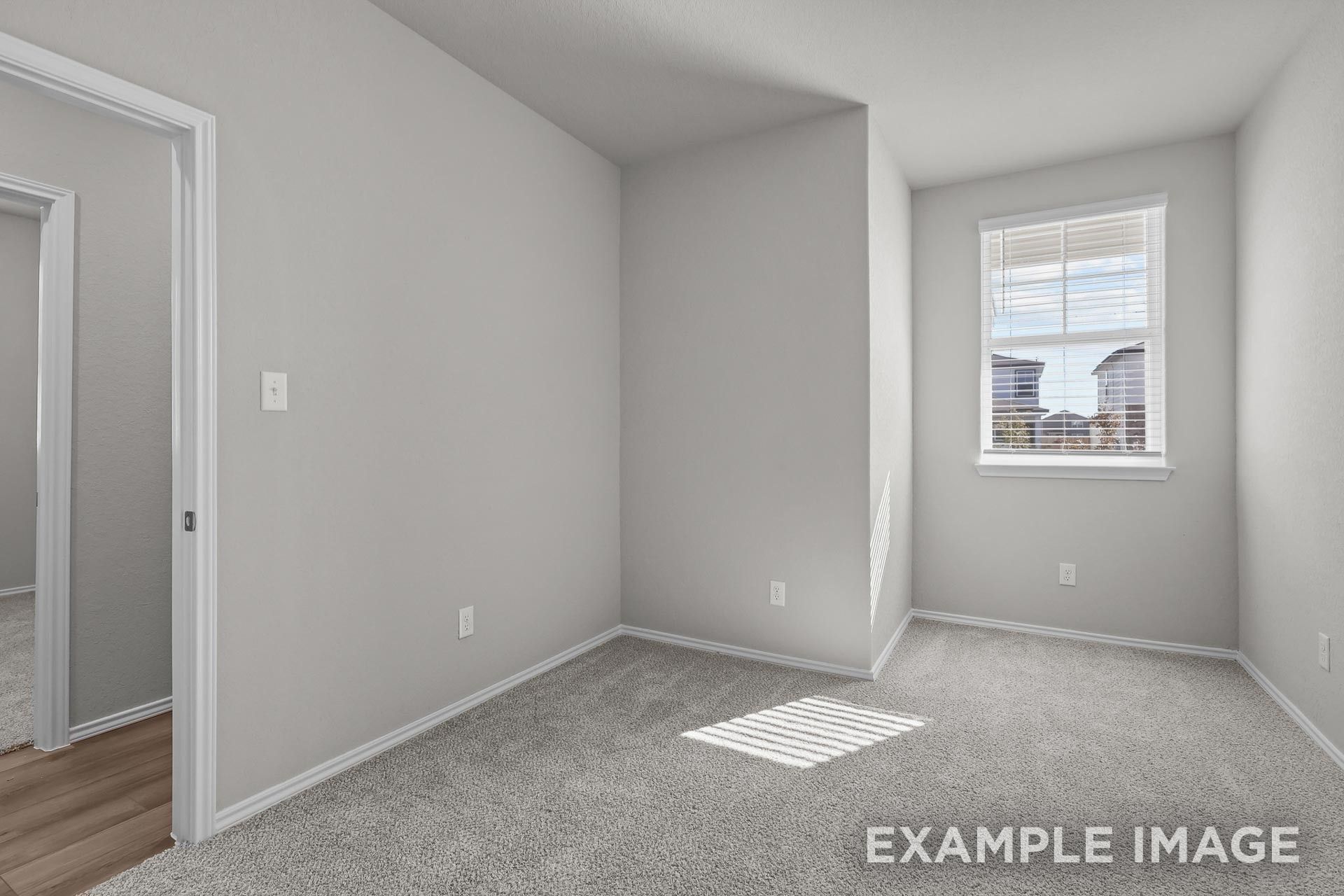 Bright, carpeted bedroom with neutral walls and window in The Colorado G floor plan by Davidson Homes in Heartland, Texas.