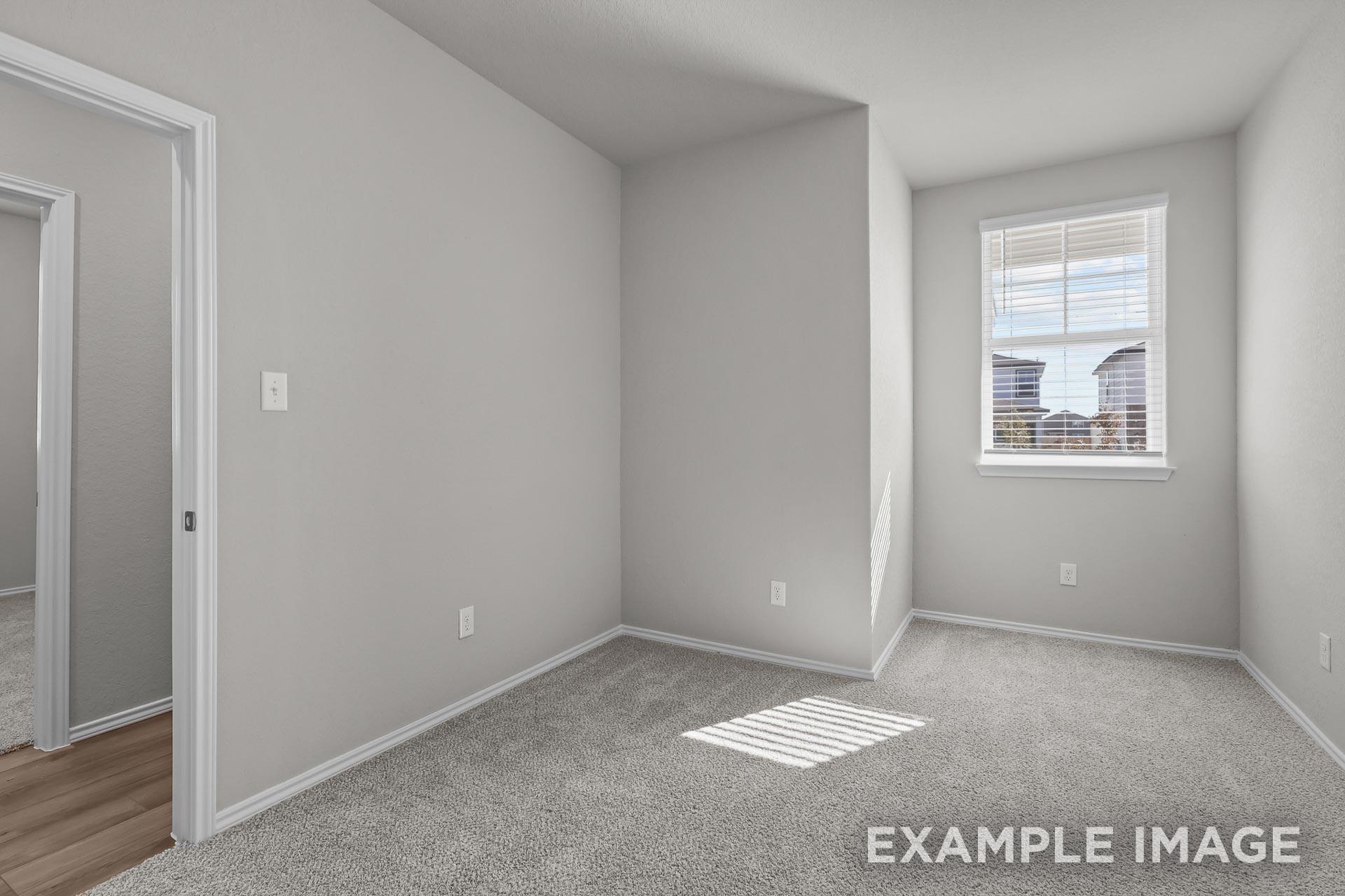Bright, carpeted bedroom with neutral walls and window in The Colorado G floor plan by Davidson Homes in Heartland, Texas.