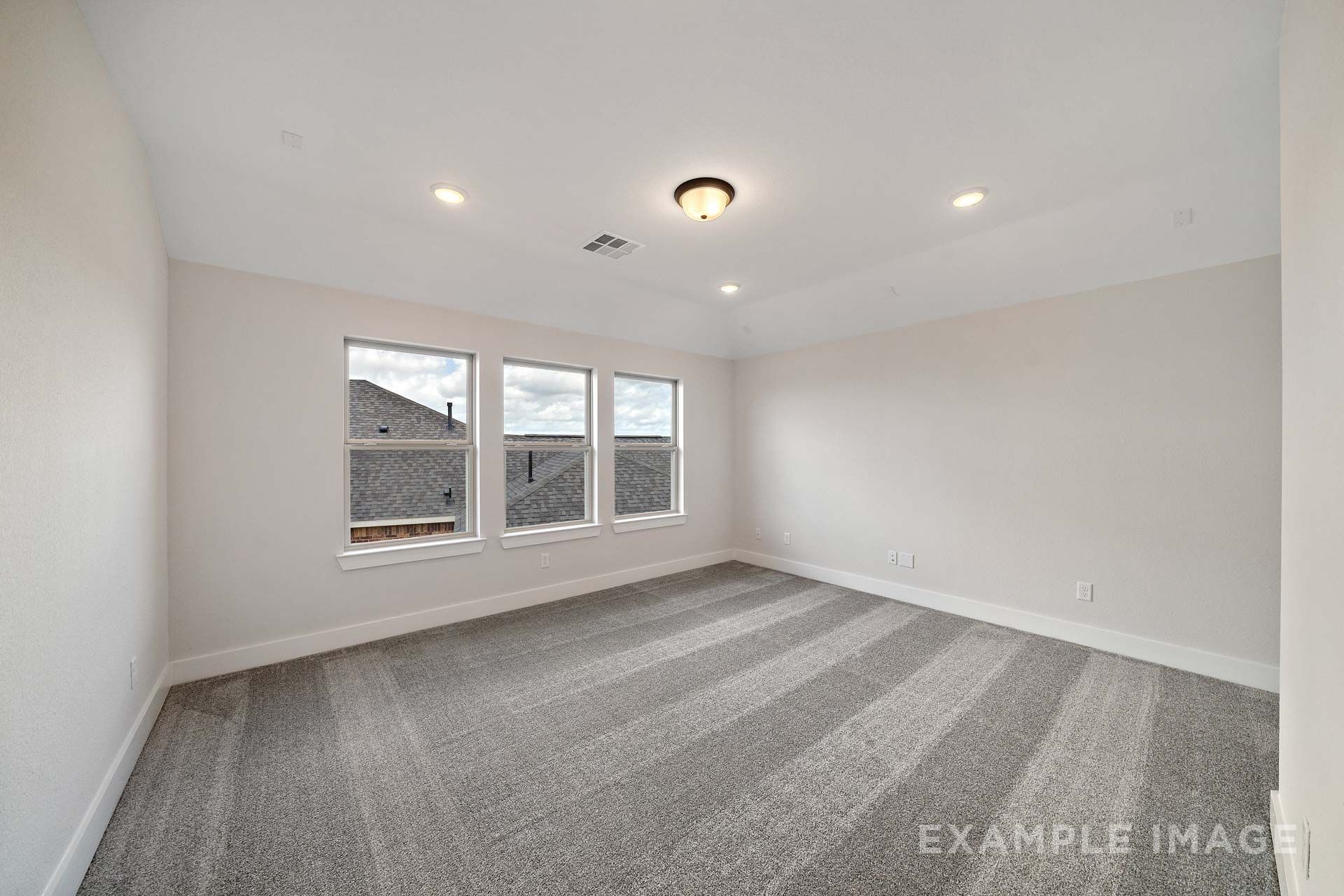 Spacious bedroom in The Victoria by Davidson Homes with gray carpet, three windows, and tray ceiling in Texas City, TX
