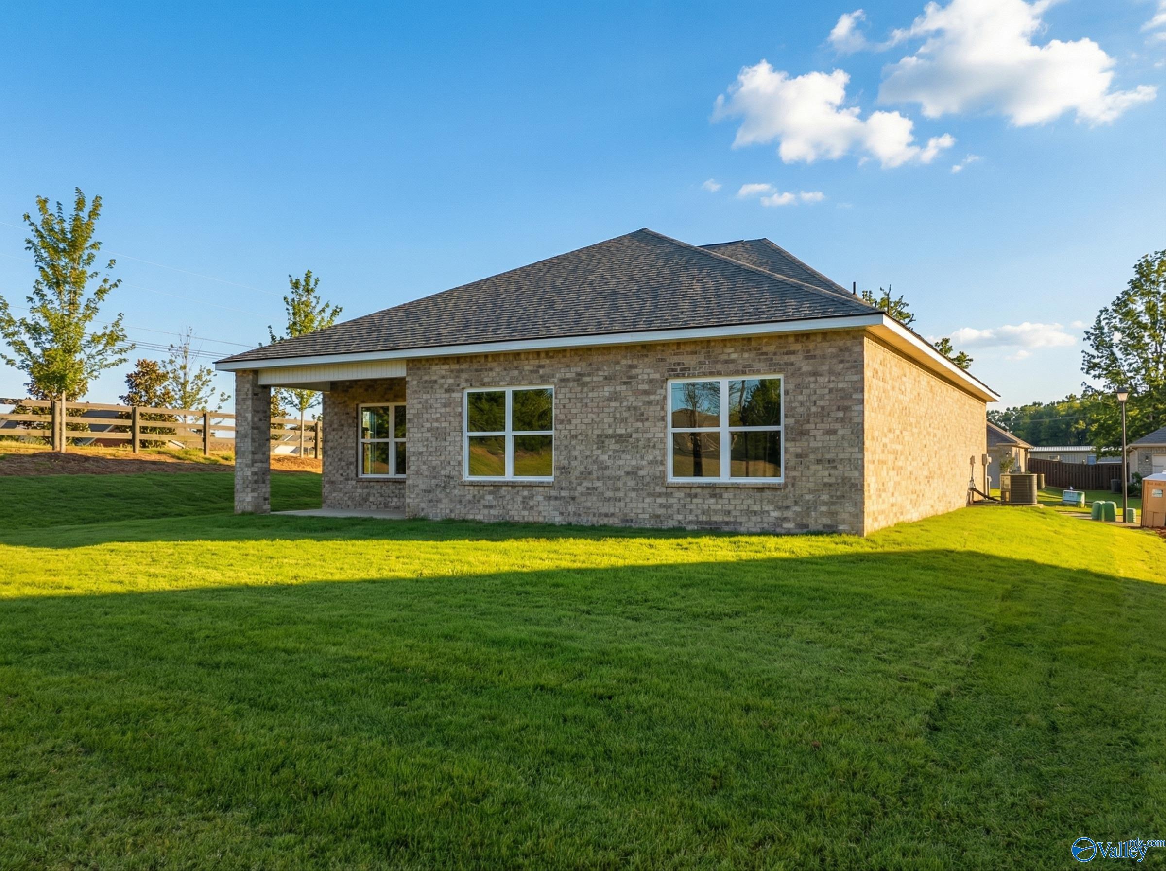Brick single-story home with gabled roof, attached garage, and lush green lawn in Flint Meadows, New Market, Alabama
