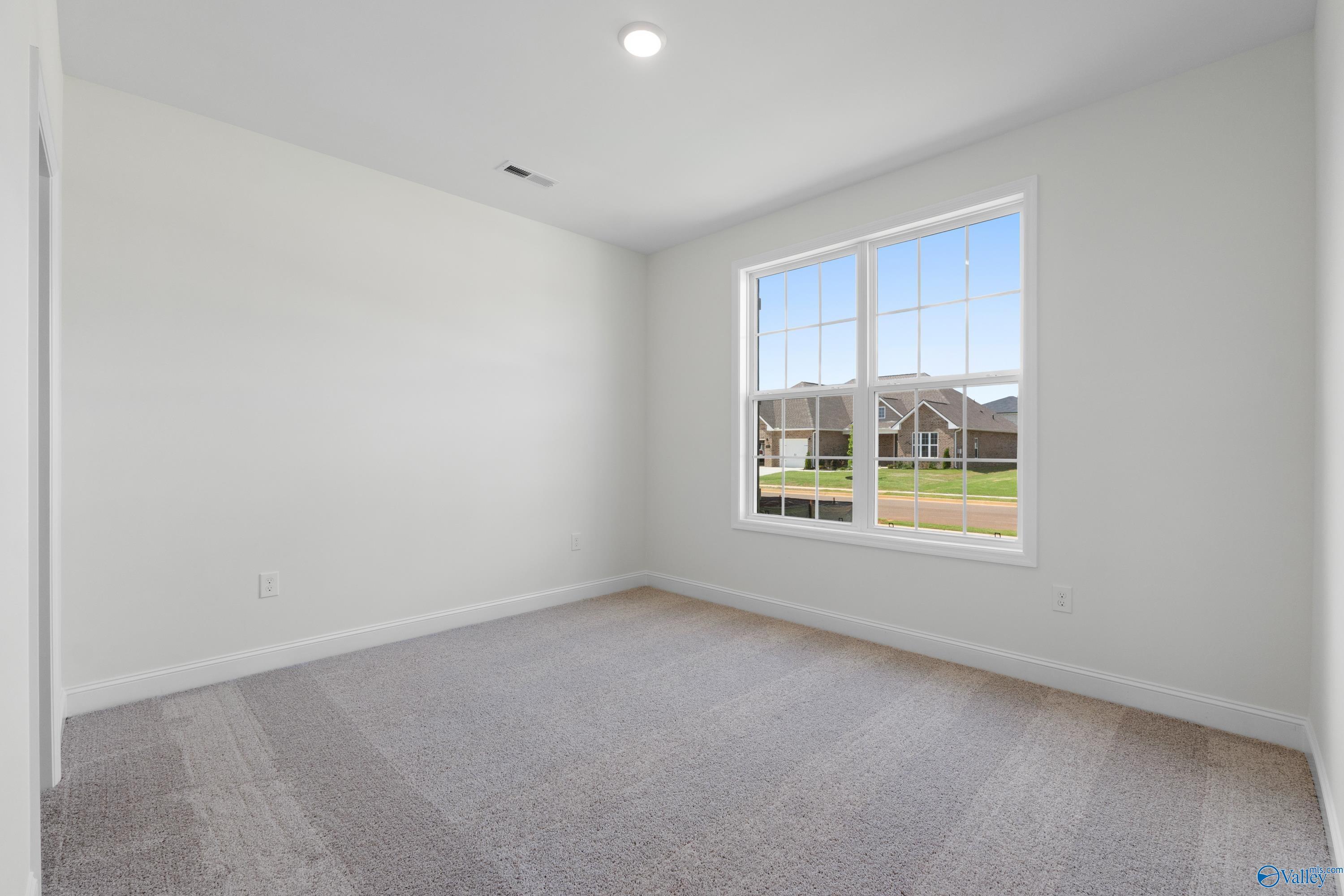 Bright bedroom with large window overlooking neighborhood and green field in Davidson Homes The Rockford B, Toney, Alabama