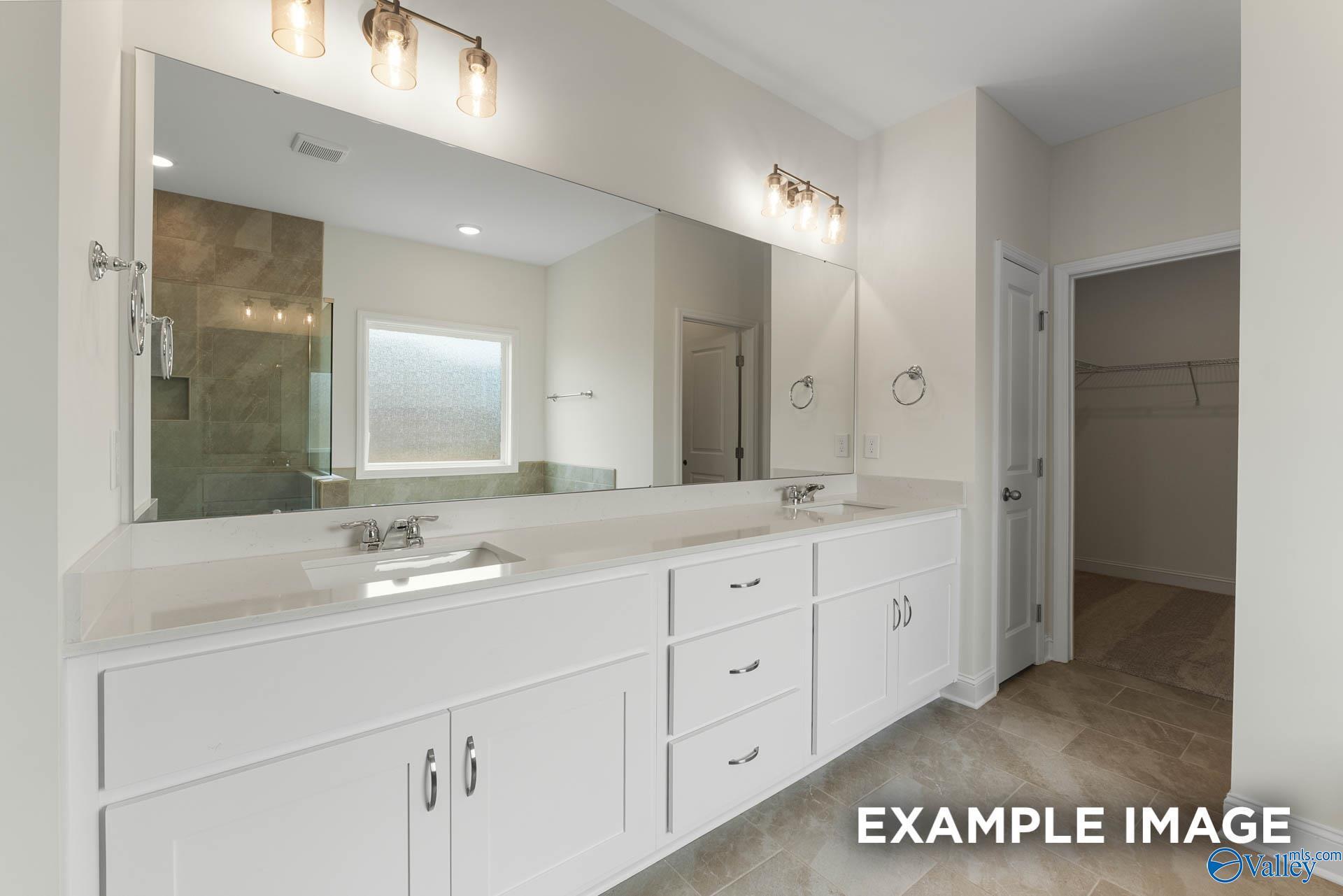 Elegant master bath with double white vanity, large mirror, glass shower, and closet in Davidson Homes The Emory, Toney, Alabama
