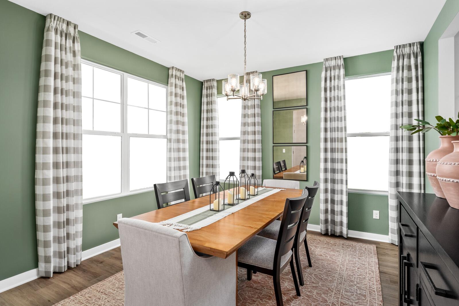 Spacious dining room at Calista Farms in White House TN with sage green walls, plaid curtains, wooden table, chandelier, and candle centerpiece