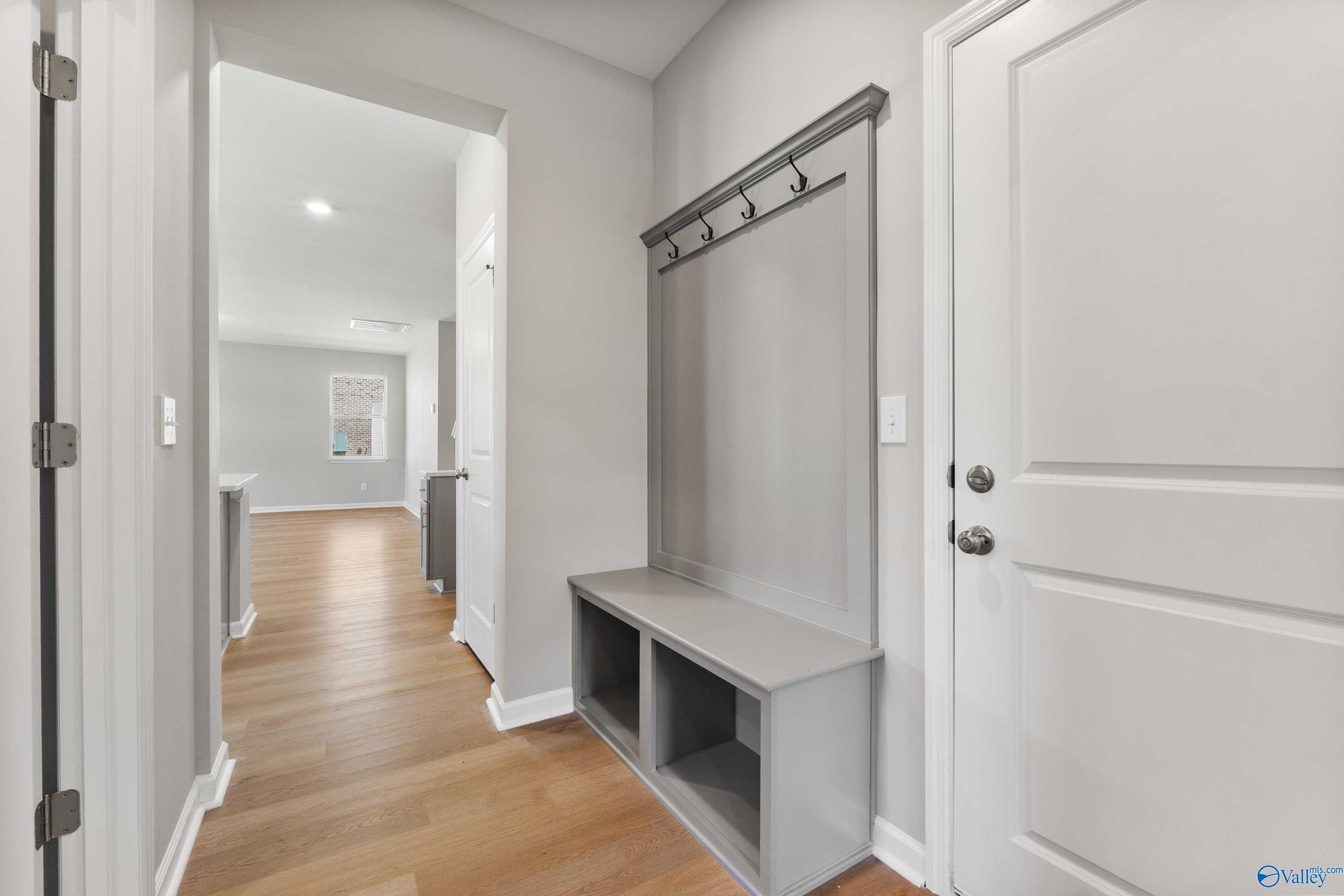 Modern entryway with gray built-in bench, coat hooks, and hardwood floors in Davidson Homes The Charm, Riverton Preserve, Huntsville