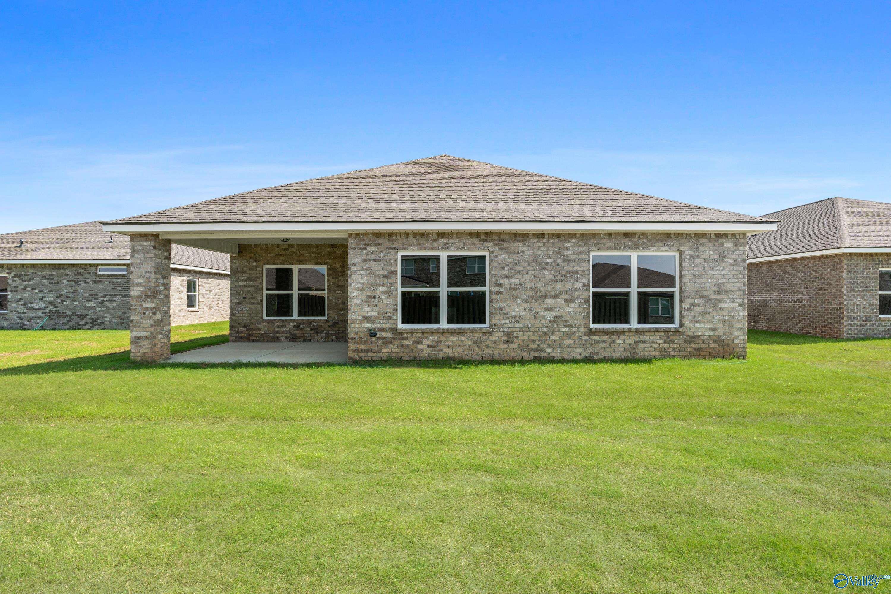 Modern single-story brick home with gabled roof, covered porch, and lush green lawn in Ivy Hills, Toney, Alabama - The Everett B by Davidson Homes