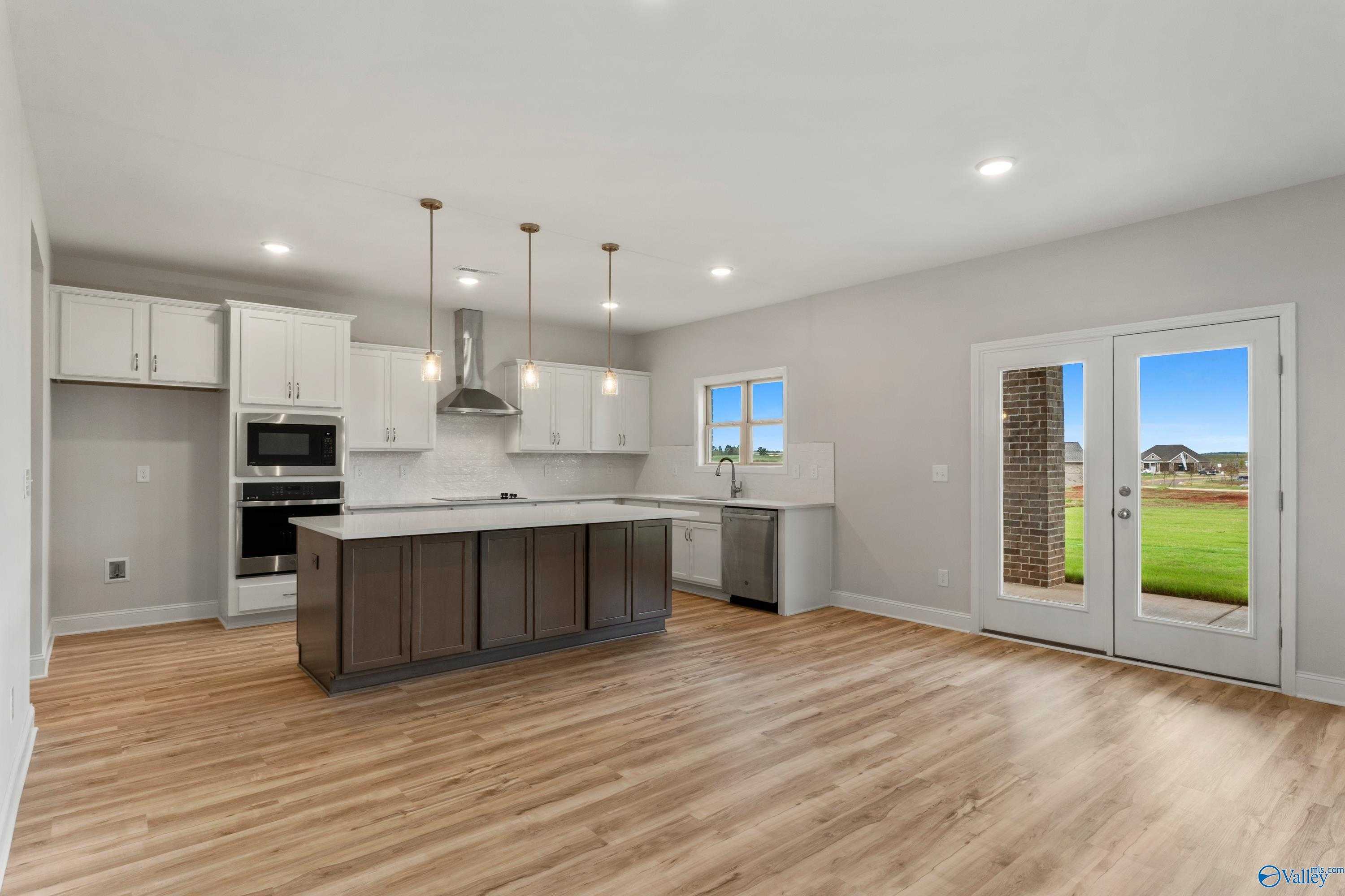Modern kitchen with white shaker cabinets, stainless steel appliances, and granite island in Davidson Homes The Chelsea C, Harvest, AL