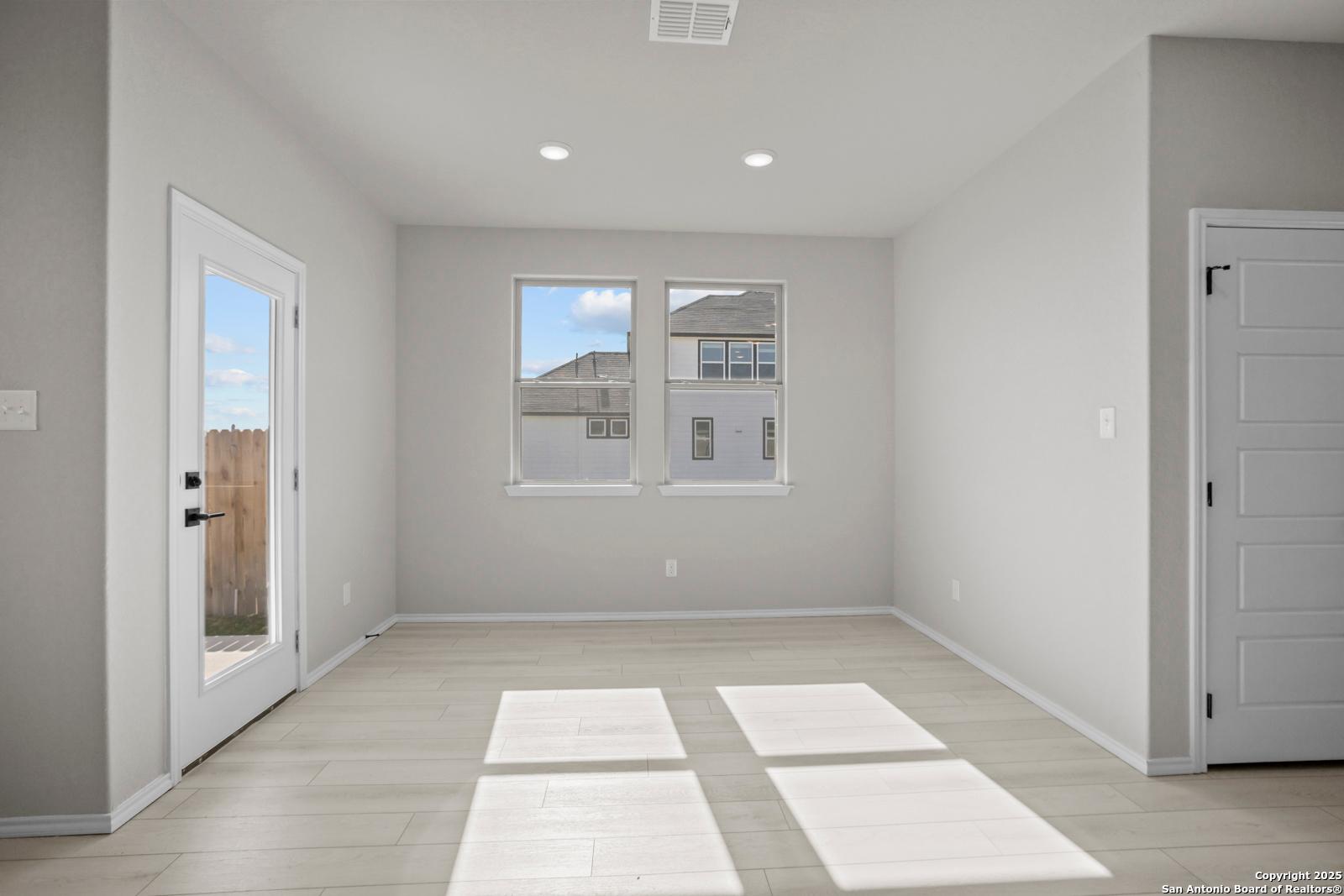 Sunlit living room with French doors to fenced backyard and large windows in Davidson Homes The Daphne H, Seguin, Texas
