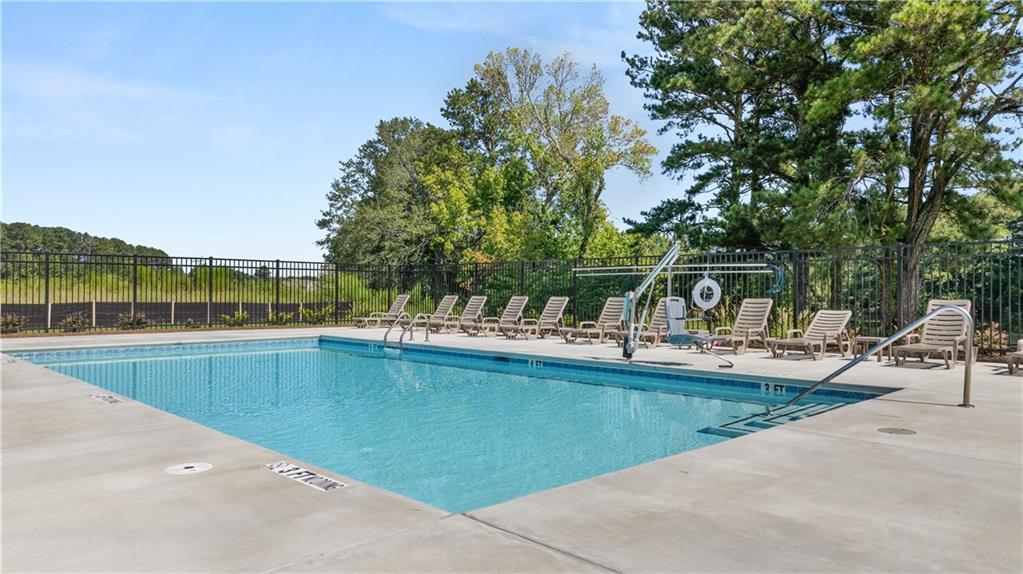 Community swimming pool with lounge chairs surrounded by trees at Lake Shore in Winder, Georgia by Davidson Homes