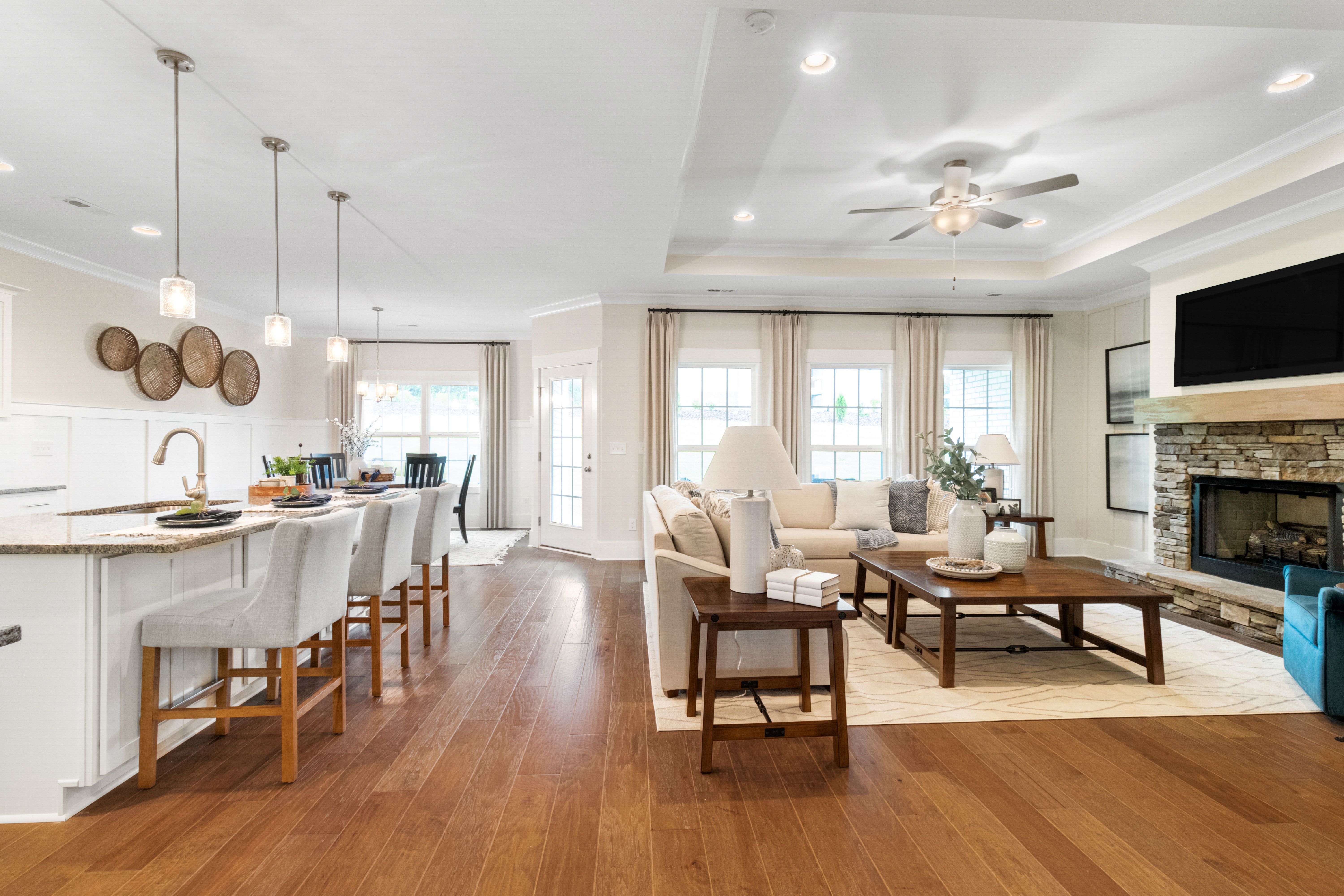 Open-concept kitchen and living room at Noble Ridge in Cullman Alabama with hardwood floors stone fireplace and island bar
