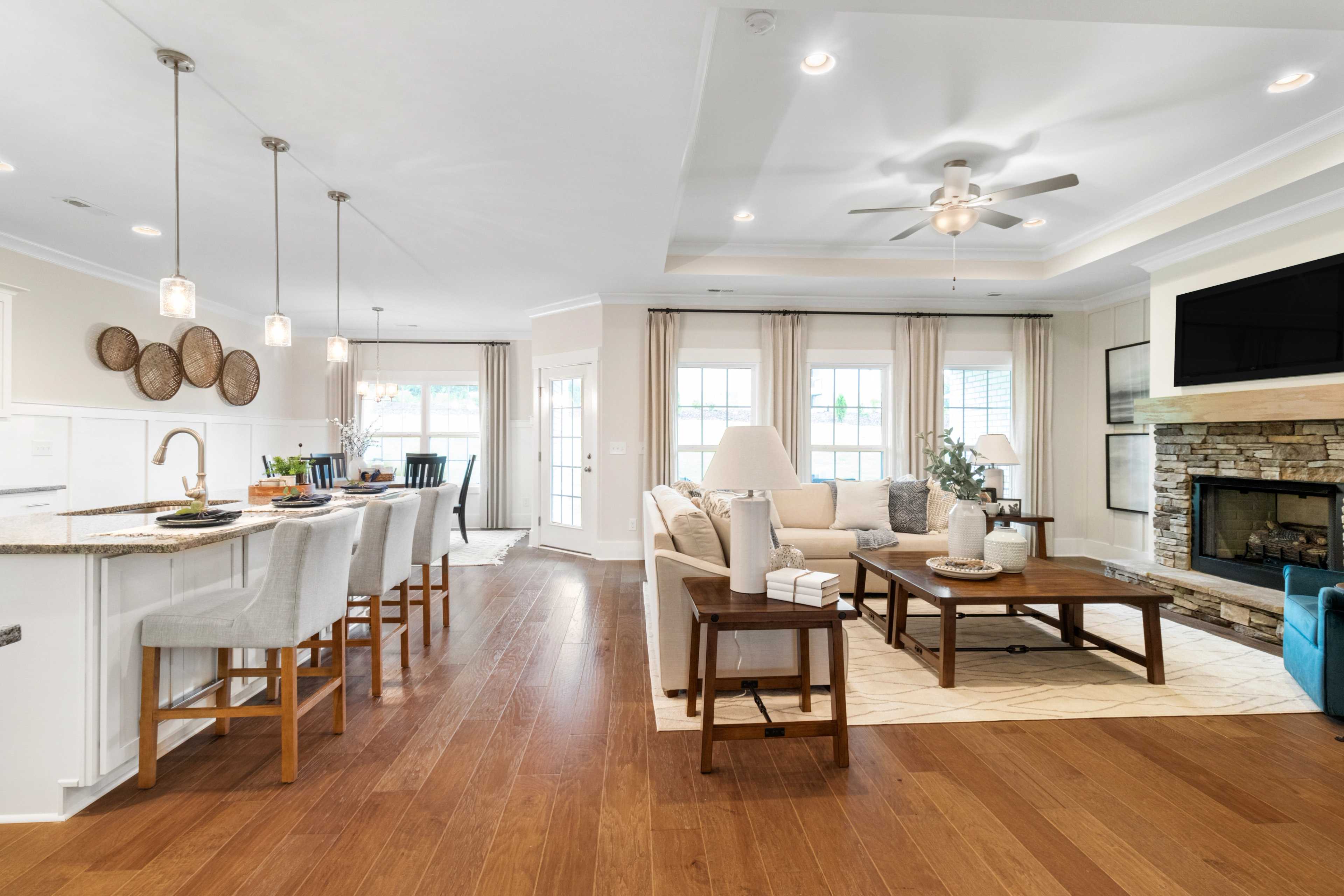 Open-concept kitchen and living room at Noble Ridge in Cullman Alabama with hardwood floors stone fireplace and island bar