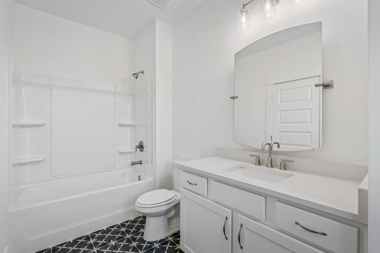 Bright white guest bathroom with double vanity, deep tub, and patterned tile floor in Davidson Homes The Hawkins, Murfreesboro, TN