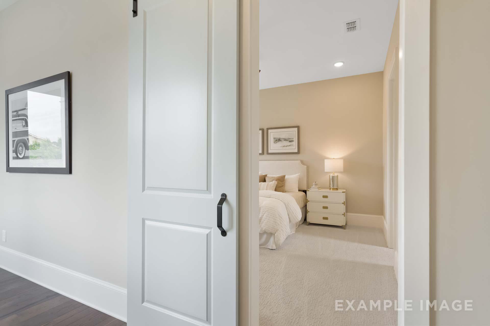 Spacious master bedroom in The Seaside C with king bed, white nightstands, neutral walls, and open doorway