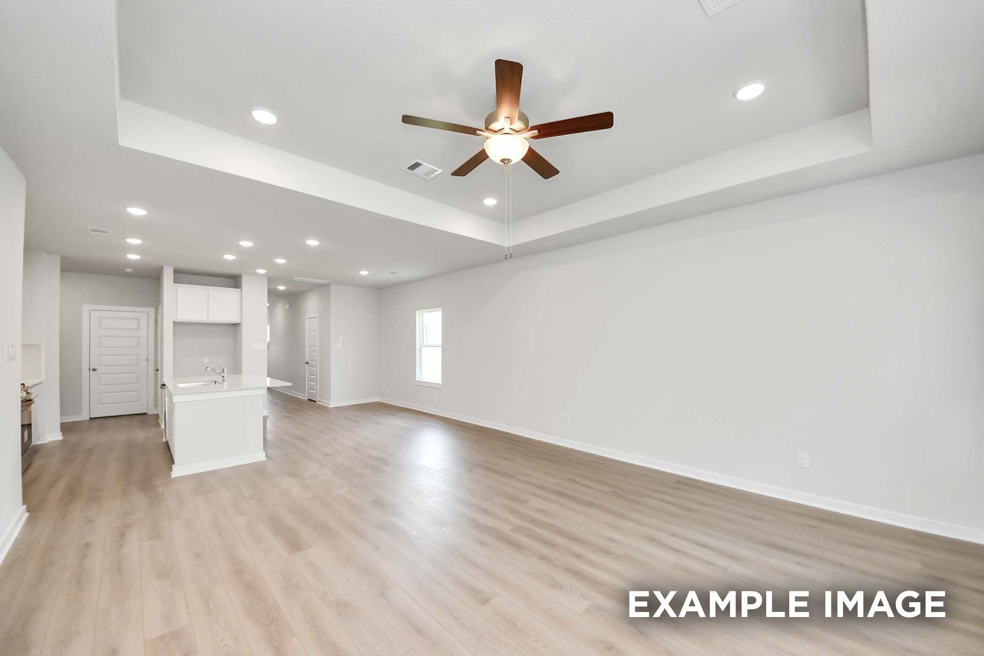 Open-concept living area in The Blanco by Davidson Homes featuring tray ceiling, ceiling fan, and luxury vinyl plank flooring