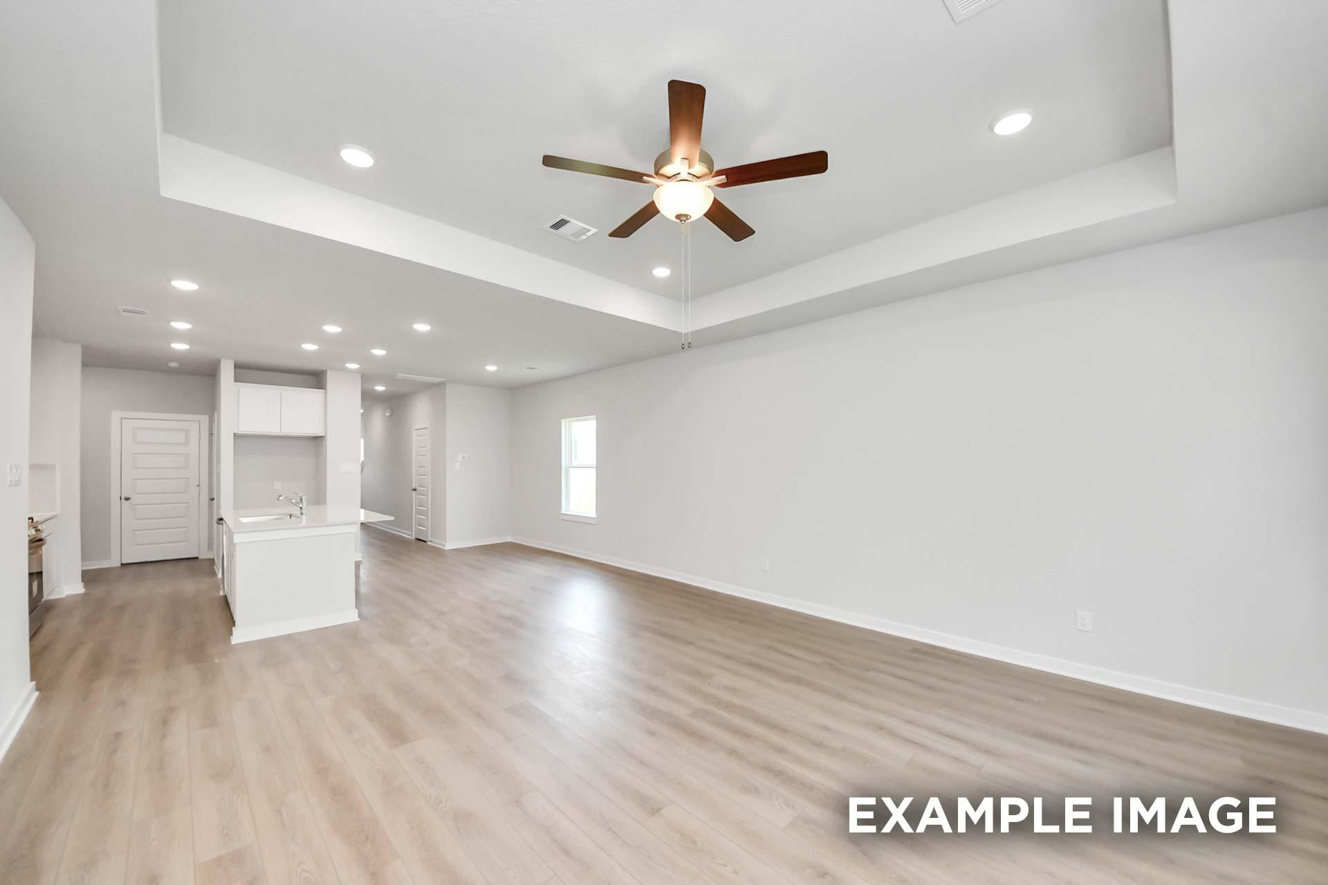 Open-concept living area in The Blanco by Davidson Homes featuring tray ceiling, ceiling fan, and luxury vinyl plank flooring