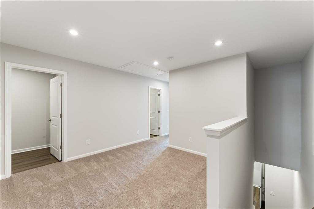 Spacious upstairs hallway with beige carpet, light gray walls, and white doors in Davidson Homes The Monroe A, Emerson, Georgia