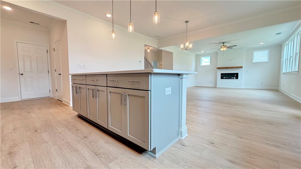 Open-concept kitchen island and living room with fireplace in The Hickory C floor plan at Wehunt Meadows, Hoschton, GA.