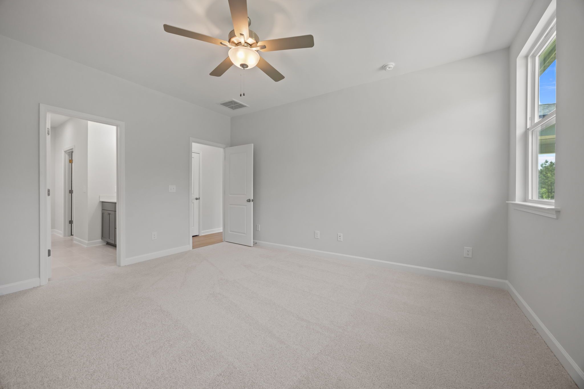 Spacious master suite on the main floor of The Ashport B, featuring plush carpeting and an en-suite bathroom.