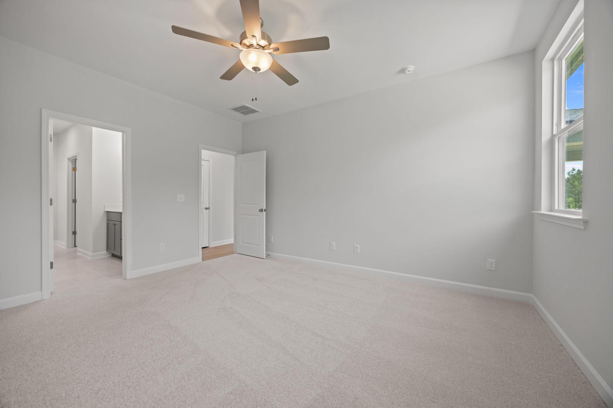 Spacious master suite on the main floor of The Ashport B, featuring plush carpeting and an en-suite bathroom.