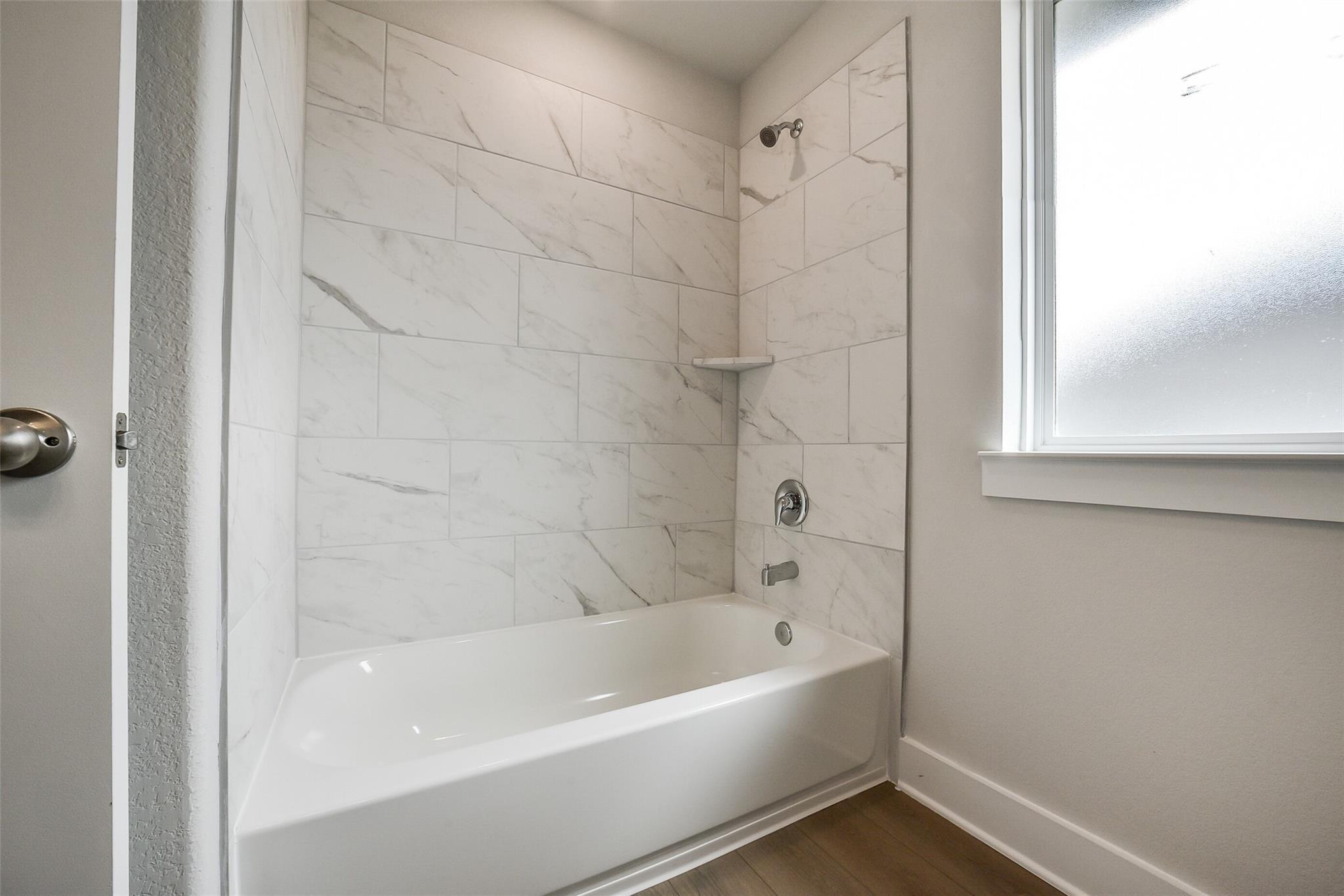 Elegant white subway tile bathroom with soaking tub and shower in Davidson Homes The Philip B, Rosharon, Texas