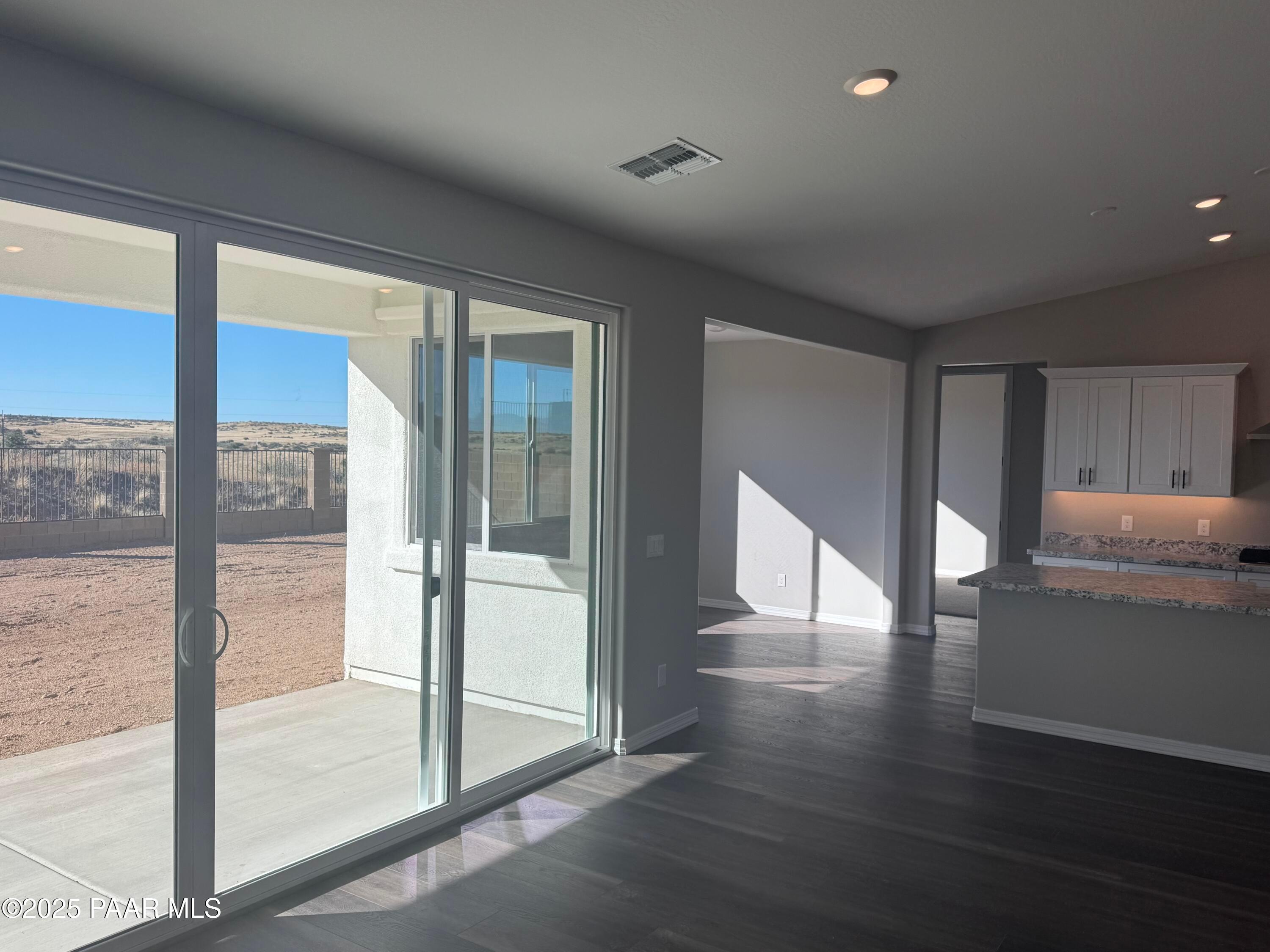 Bright living area with sliding glass doors to desert patio view and white cabinet kitchen in The Monarch E, Westwood Prescott AZ