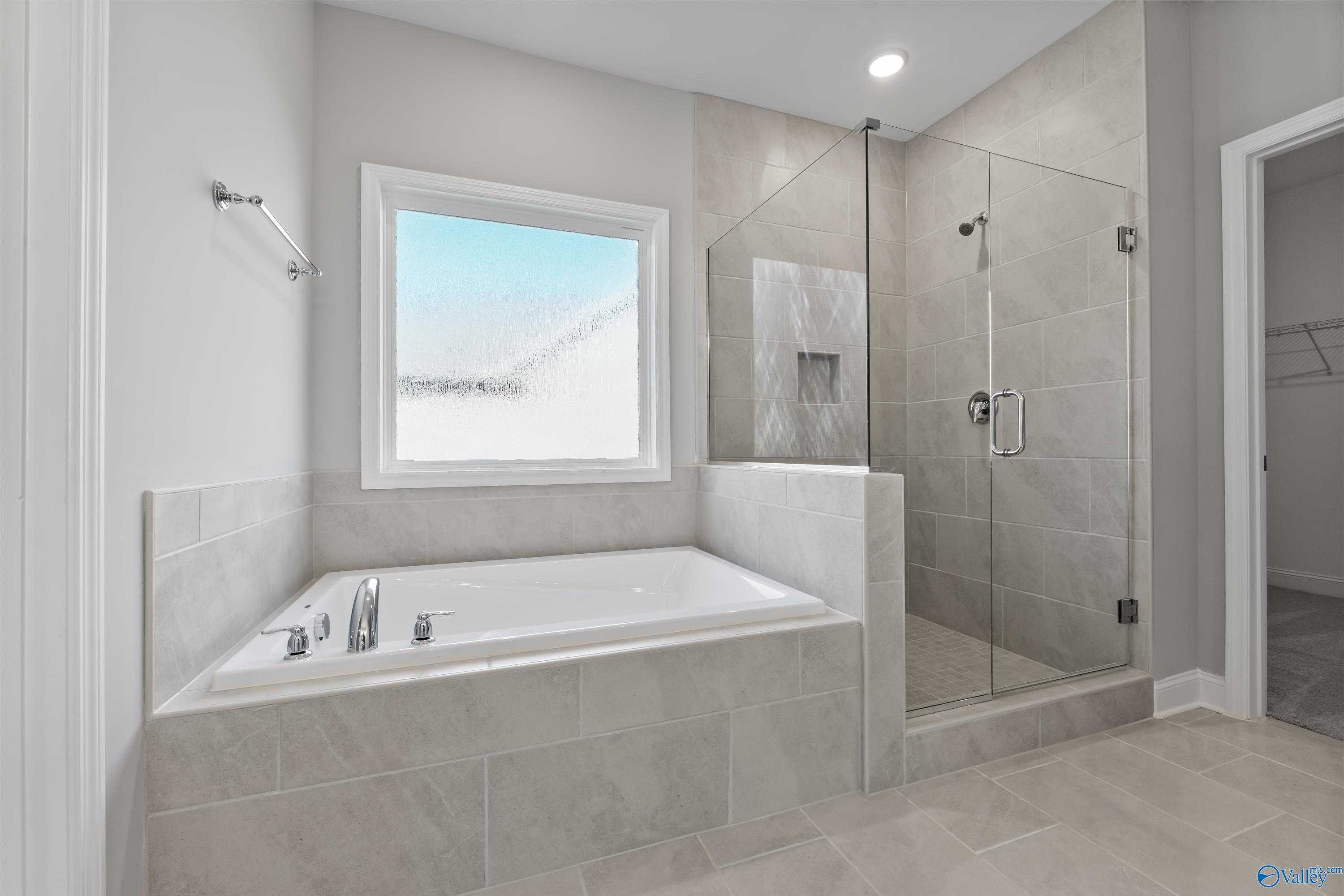 Luxurious master bathroom with freestanding tub, glass shower enclosure, and tiled accents in Davidson Homes The Rockford, Harvest, AL