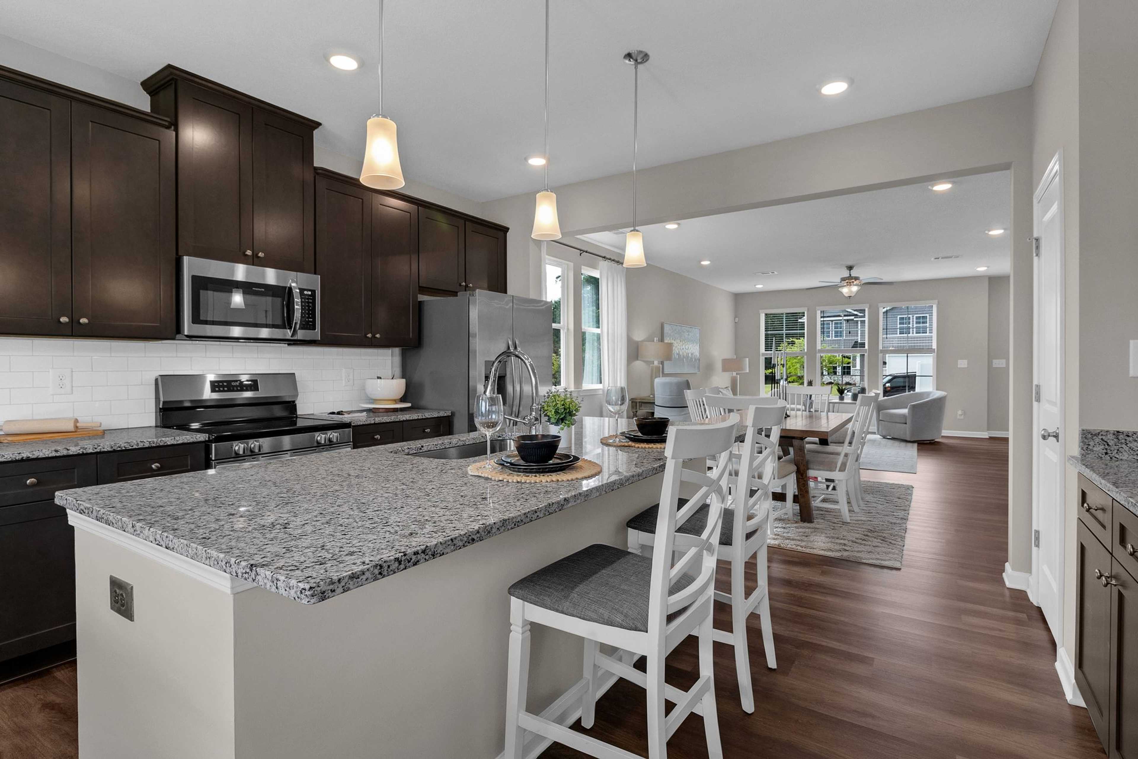 Spacious open-concept kitchen at Ivy Glen in Perry Georgia with granite island, dark cabinets, and hardwood floors
