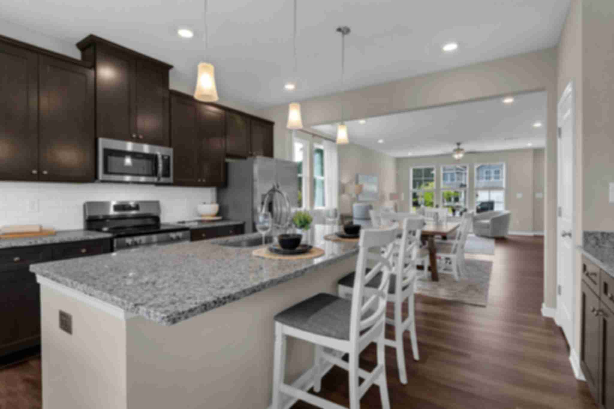 Spacious open-concept kitchen at Ivy Glen in Perry Georgia with granite island, dark cabinets, and hardwood floors