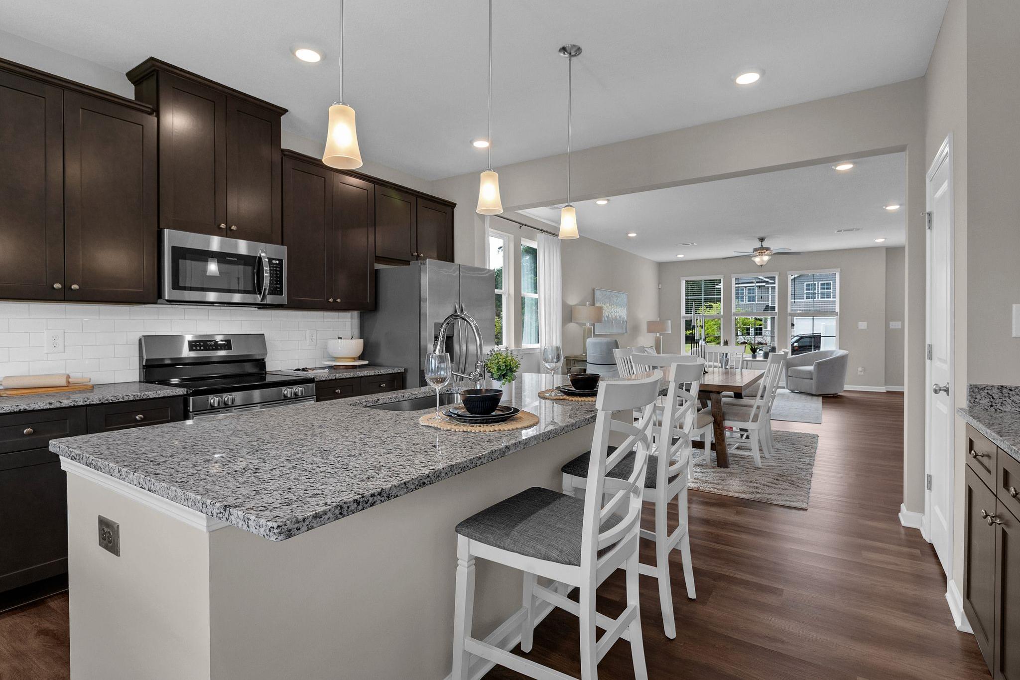 Open-concept kitchen at Ivy Glen in Perry Georgia with espresso cabinets granite island stainless appliances hardwood floors