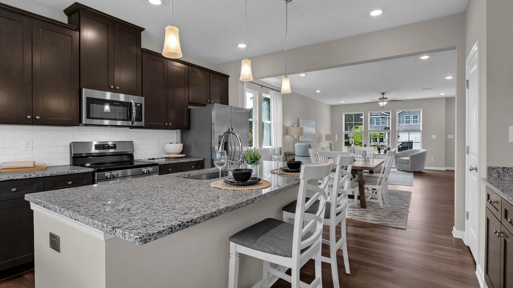 Spacious open-concept kitchen at Ivy Glen in Perry Georgia with granite island, dark cabinets, and hardwood floors