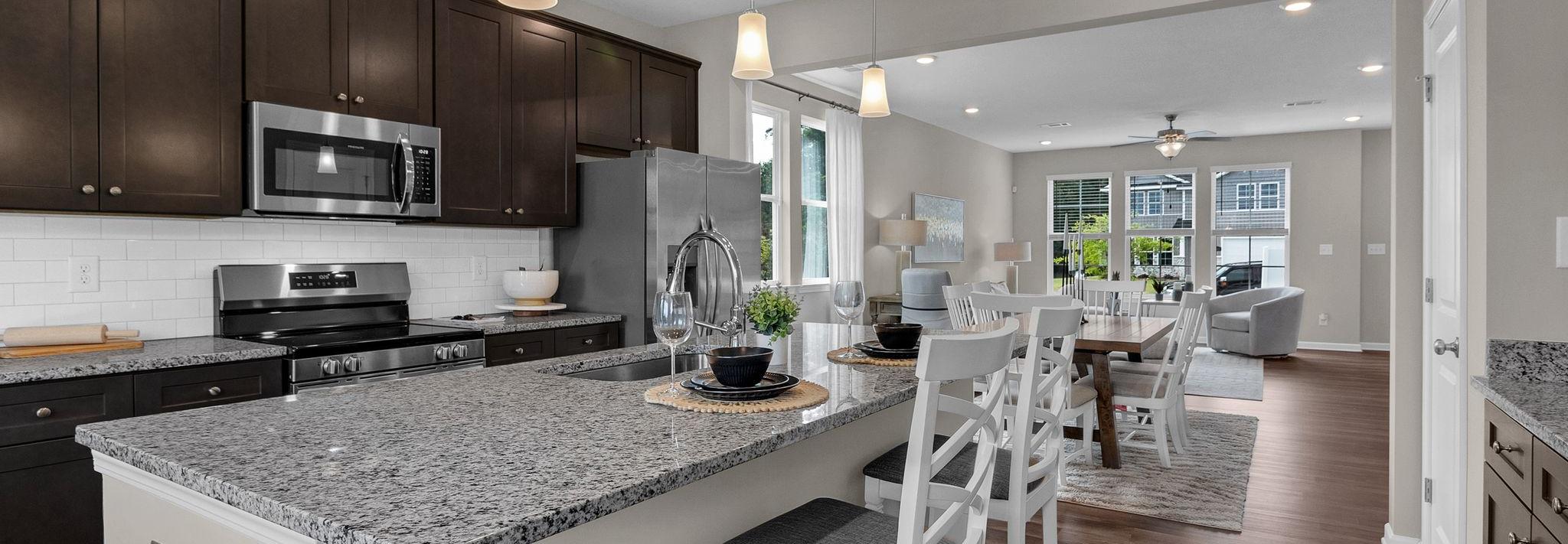 Spacious open-concept kitchen at Ivy Glen in Perry Georgia with granite island, dark cabinets, and hardwood floors