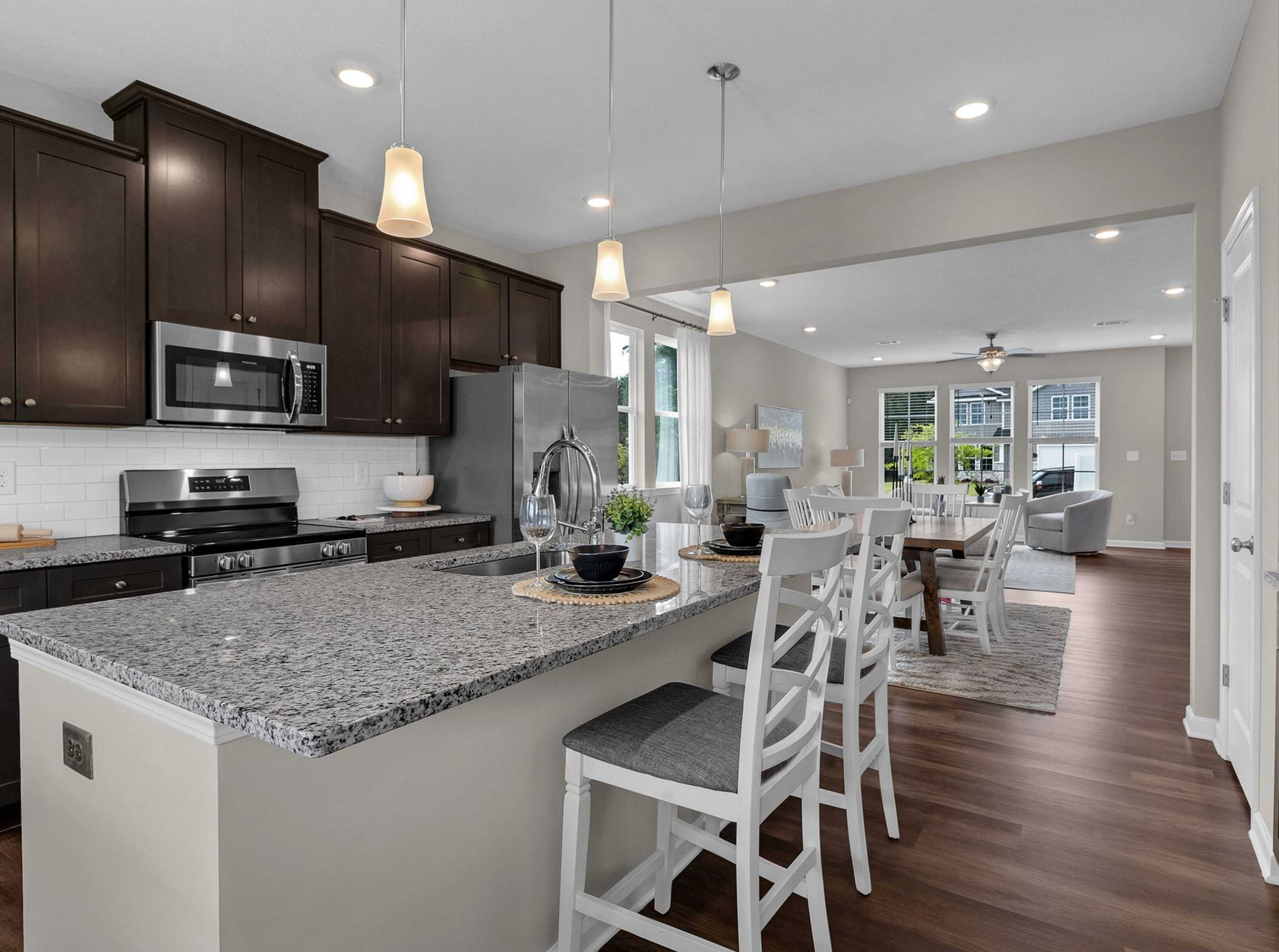Spacious open-concept kitchen at Ivy Glen in Perry Georgia with granite island, dark cabinets, and hardwood floors