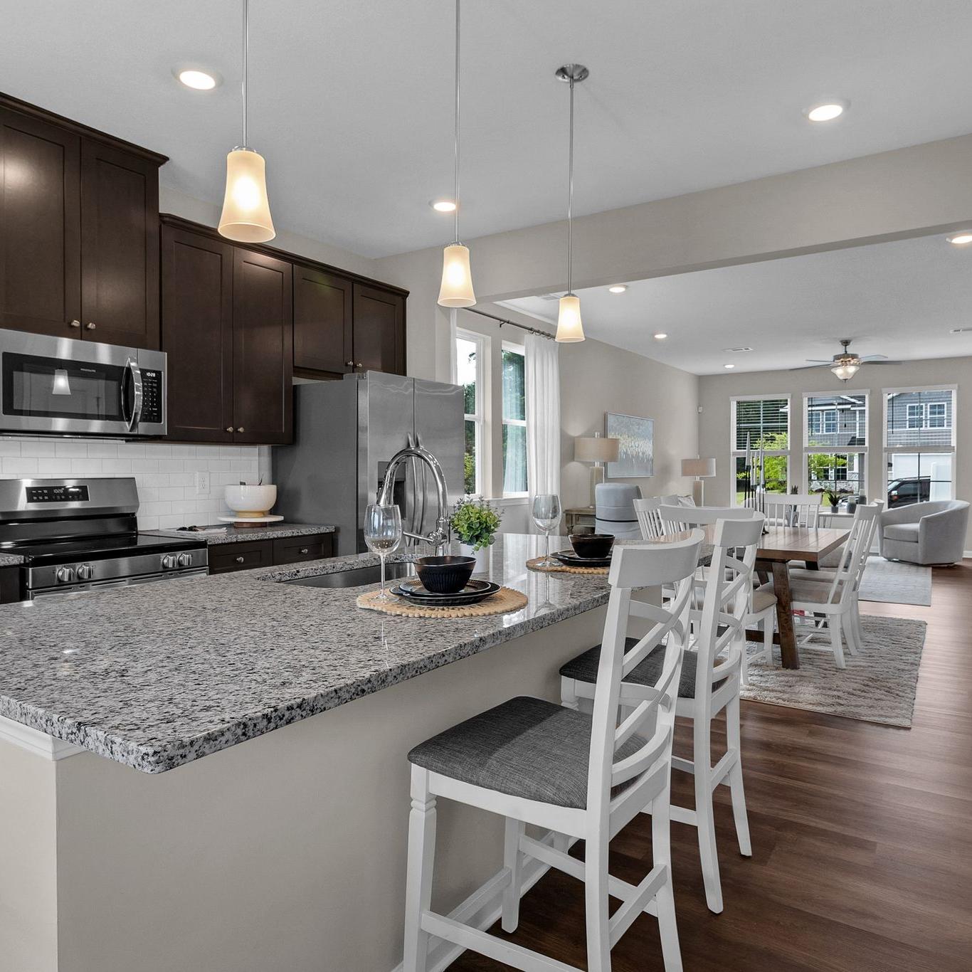 Spacious open-concept kitchen at Ivy Glen in Perry Georgia with granite island, dark cabinets, and hardwood floors