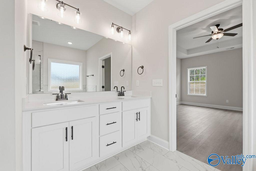 Modern master bathroom with double vanity, white shaker cabinets, mirrors, and subway tile floor in Davidson Homes The Rockford B, Hartselle, AL