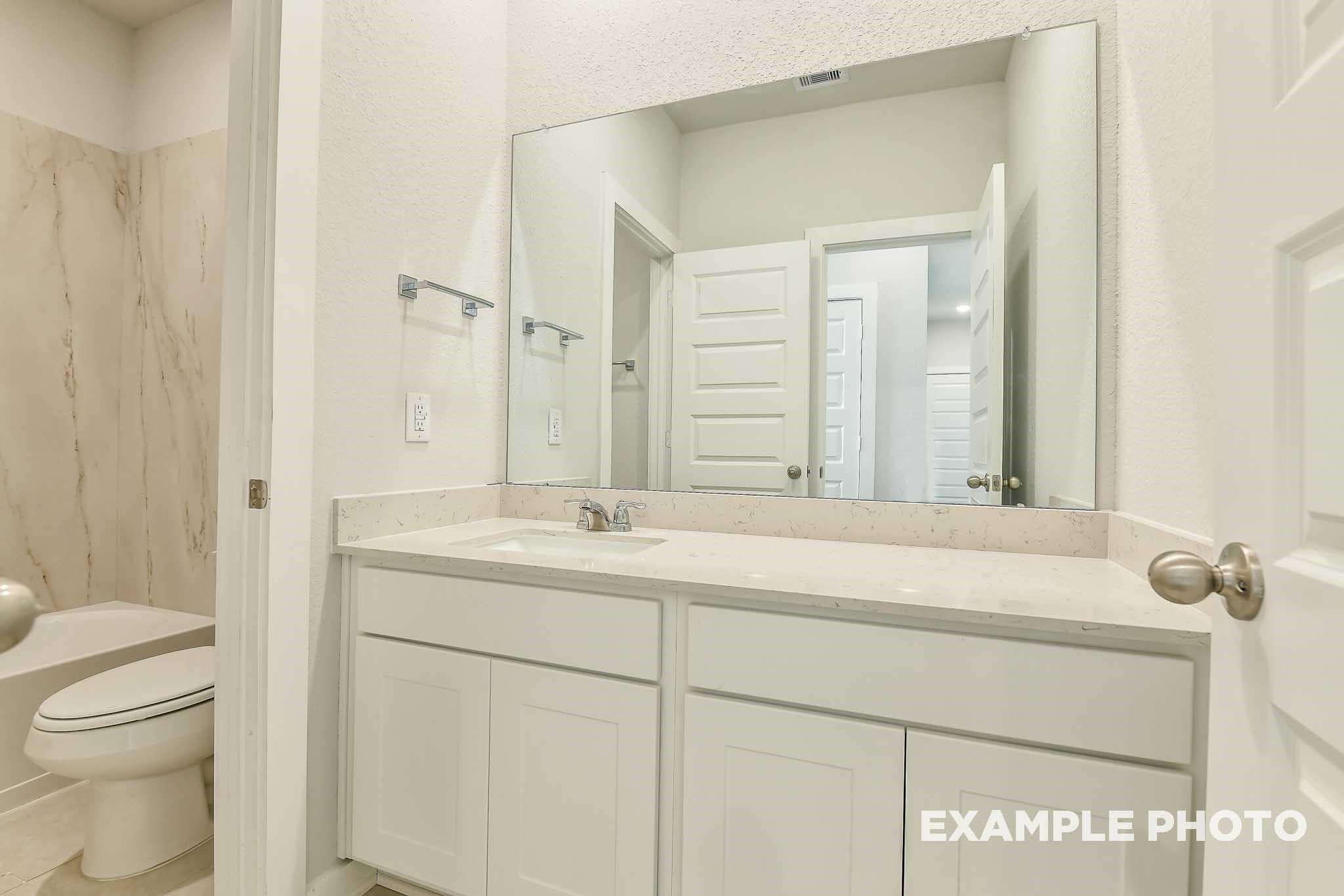 Modern master bathroom featuring double white vanity, large frameless mirror, and tiled shower in Davidson Homes The Colorado G, Conroe, Texas