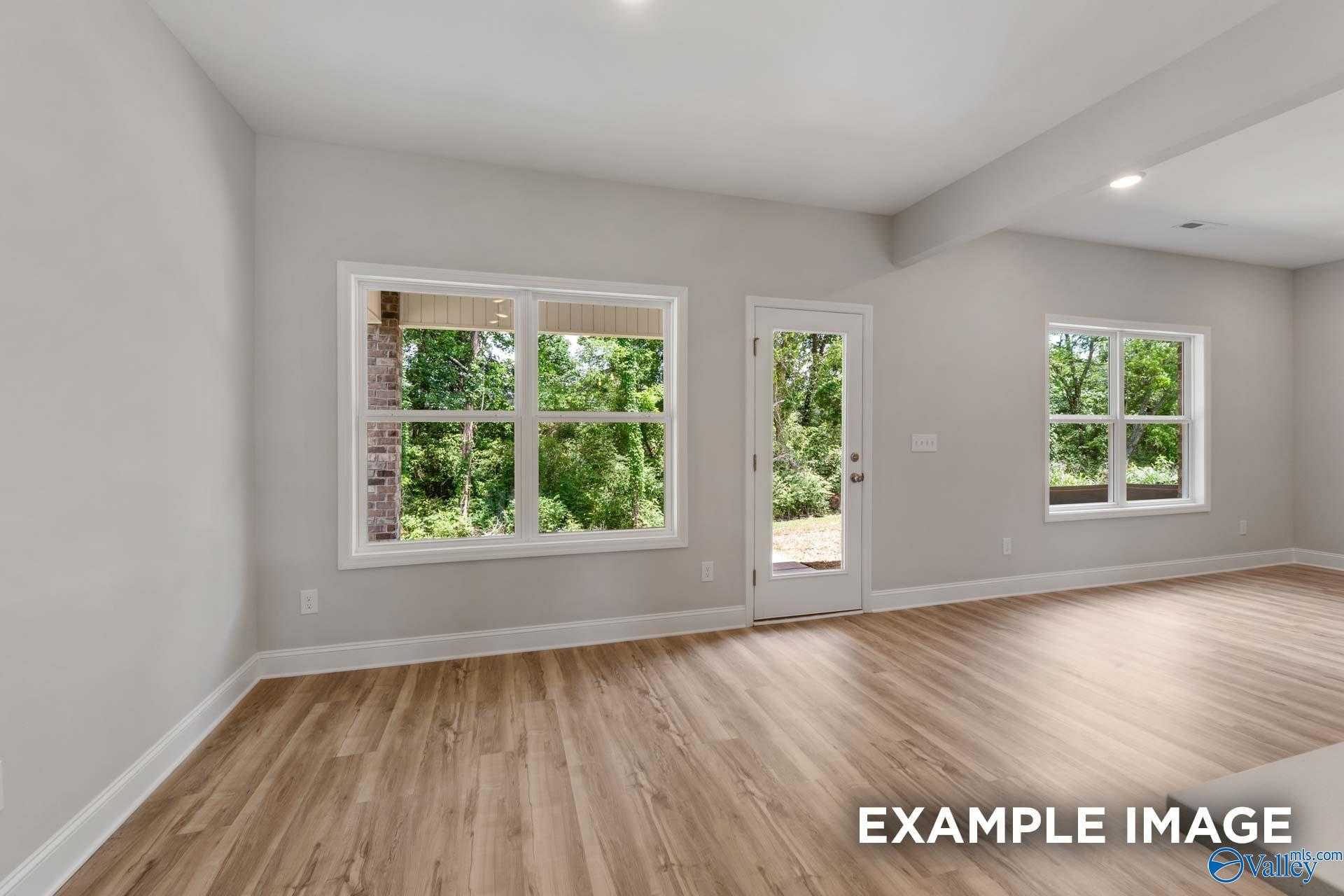 Bright family room with large windows and sliding glass door overlooking wooded backyard in Davidson Homes The Shelby C, Meridianville, Alabama