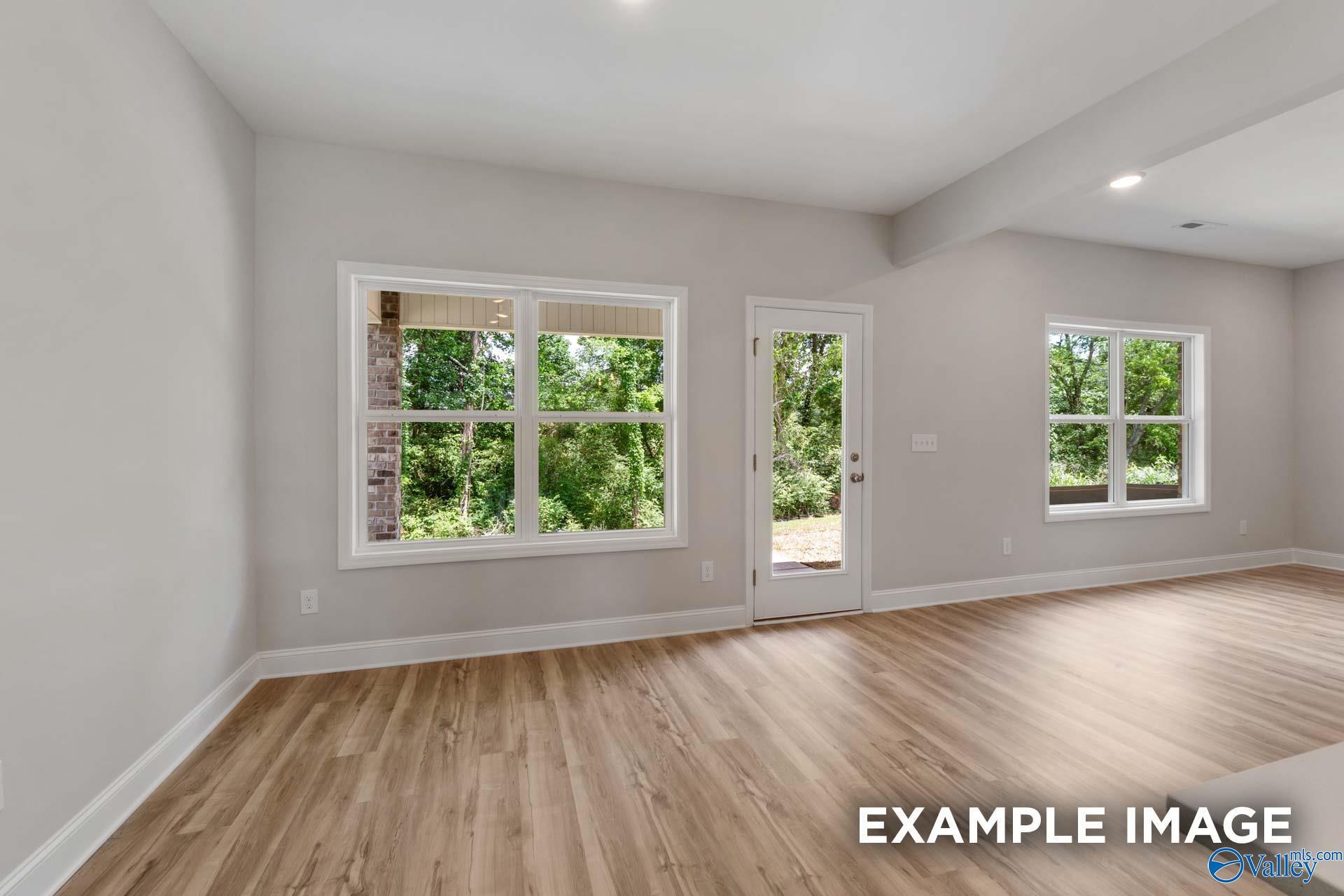 Bright family room with large windows and sliding glass door overlooking wooded backyard in Davidson Homes The Shelby C, Meridianville, Alabama