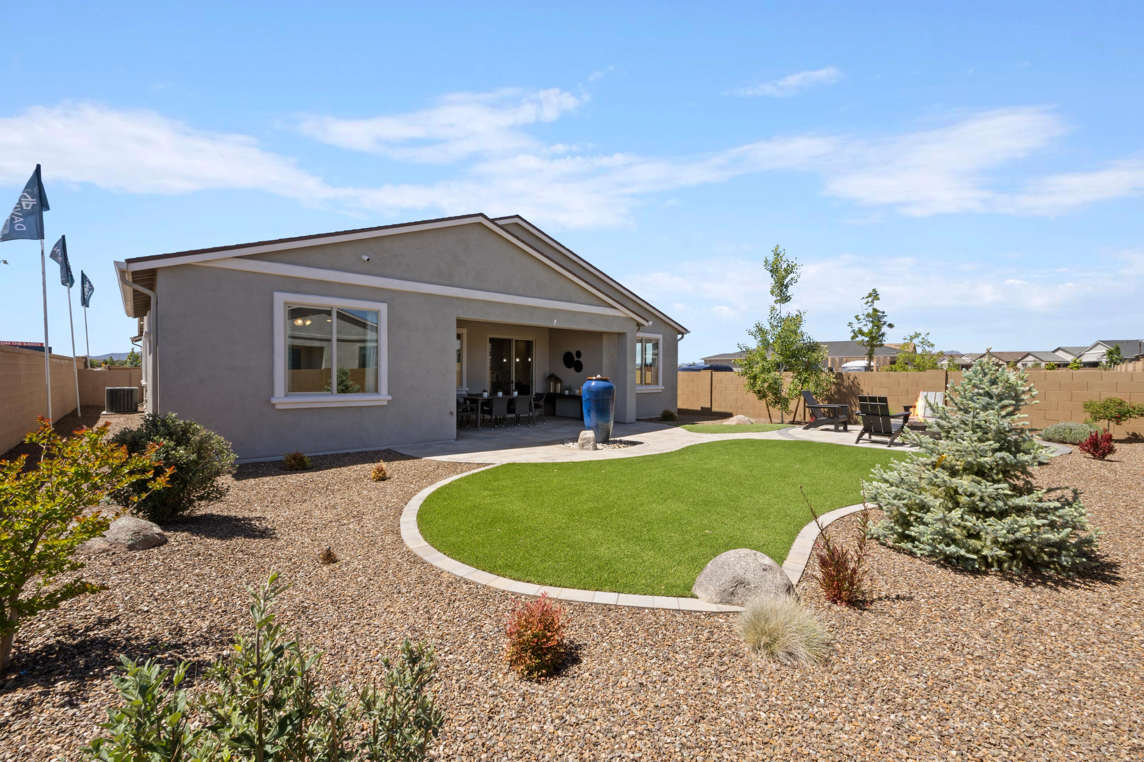 Desert backyard with curved turf lawn, covered patio, seating, and spruce trees at North Ridge in Pronghorn Ranch, Prescott Valley AZ