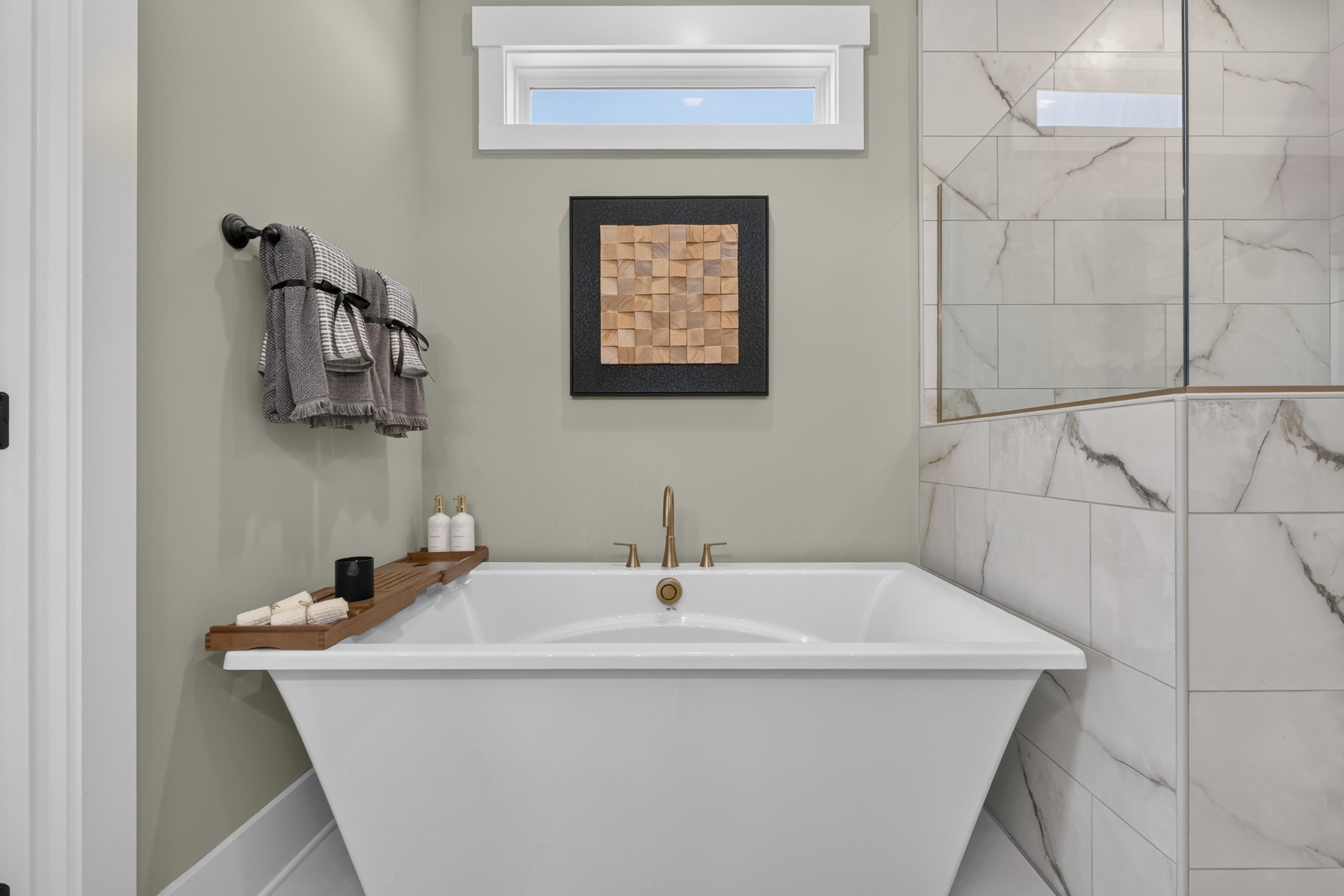 Freestanding soaking tub with brushed gold faucet in a spa bathroom at Evergreen Mill by Davidson Homes, Madison AL