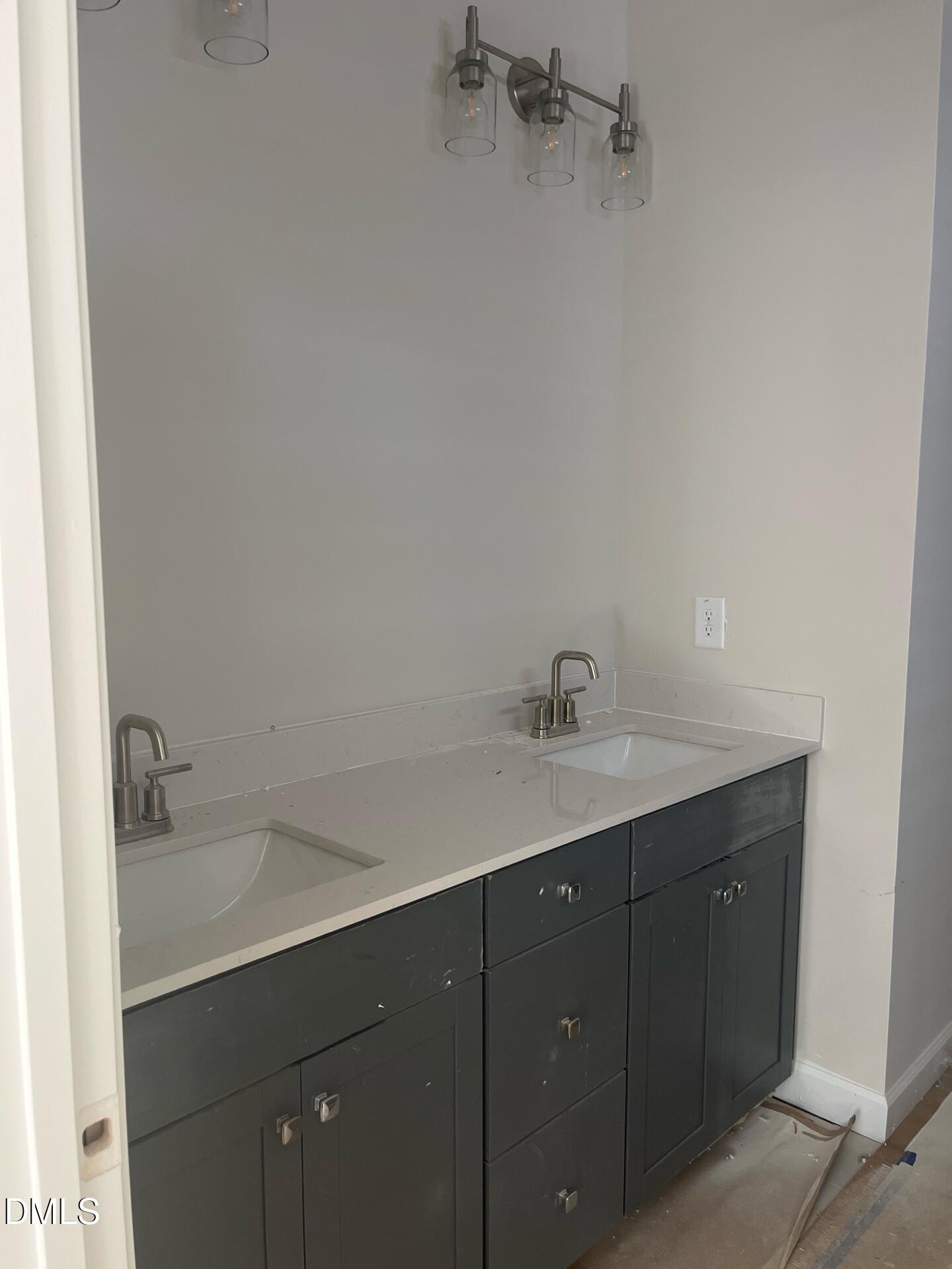 Modern double vanity with white quartz countertop, dark gray cabinets, and dual undermount sinks in The Ashport G primary bath, Wake Forest, NC
