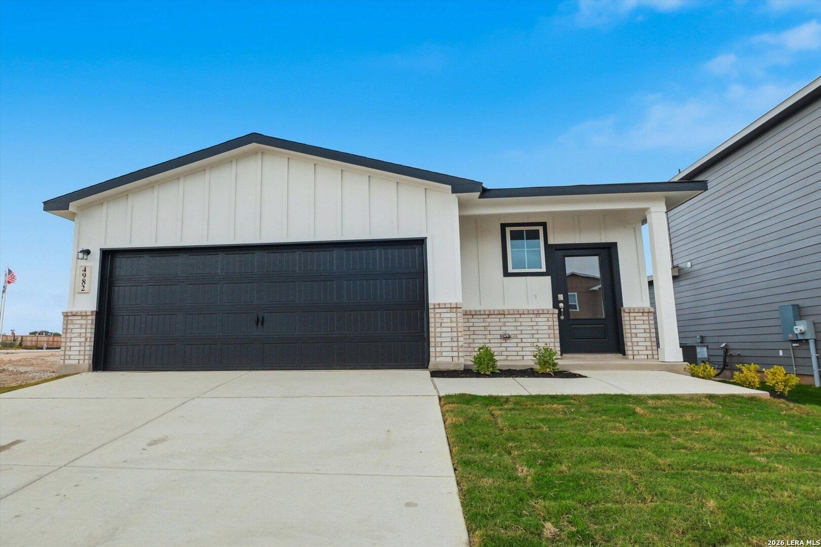Modern white shiplap single-story home with black 2-car garage, brick accents, and front entry in Agave, San Antonio - Davidson Homes The Frio B