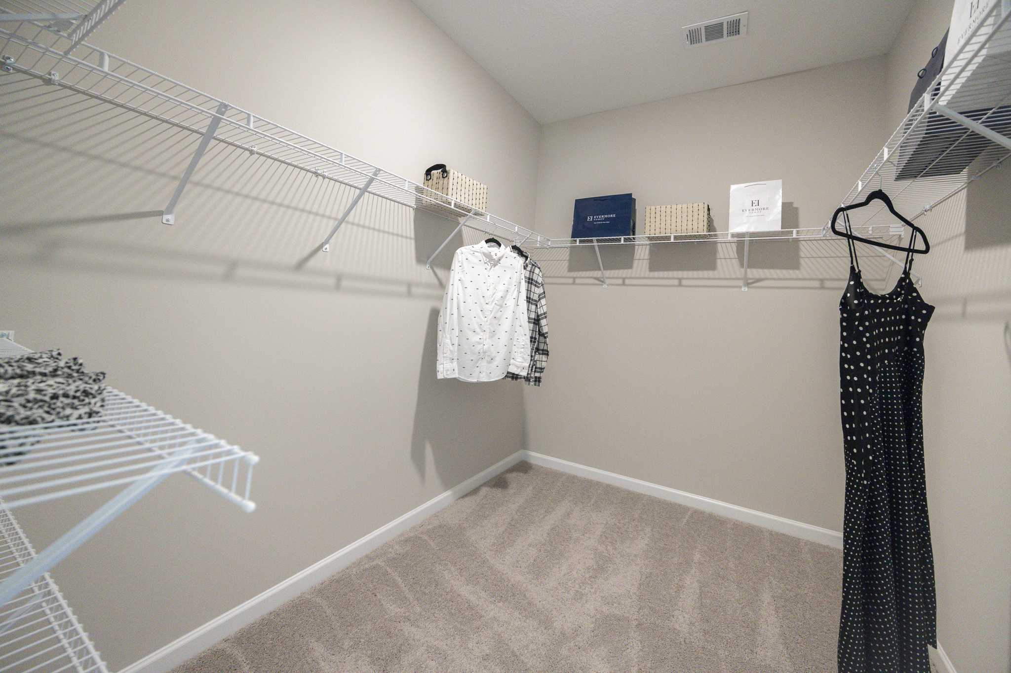 Spacious walk-in closet in Silver Oak Cusseta AL home with wire shelving, hanging clothes and storage baskets by Evermore Homes