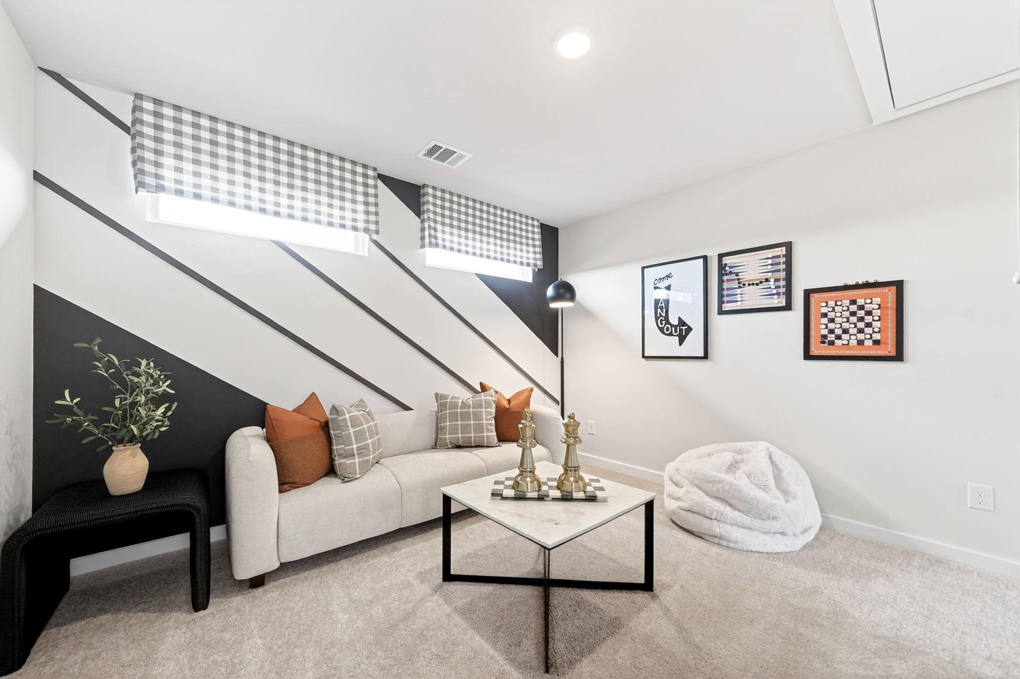 Cozy game room in Heartland Texas home with black-white striped walls, gingham curtains, beige sofa, marble chess table, and fluffy bean bag