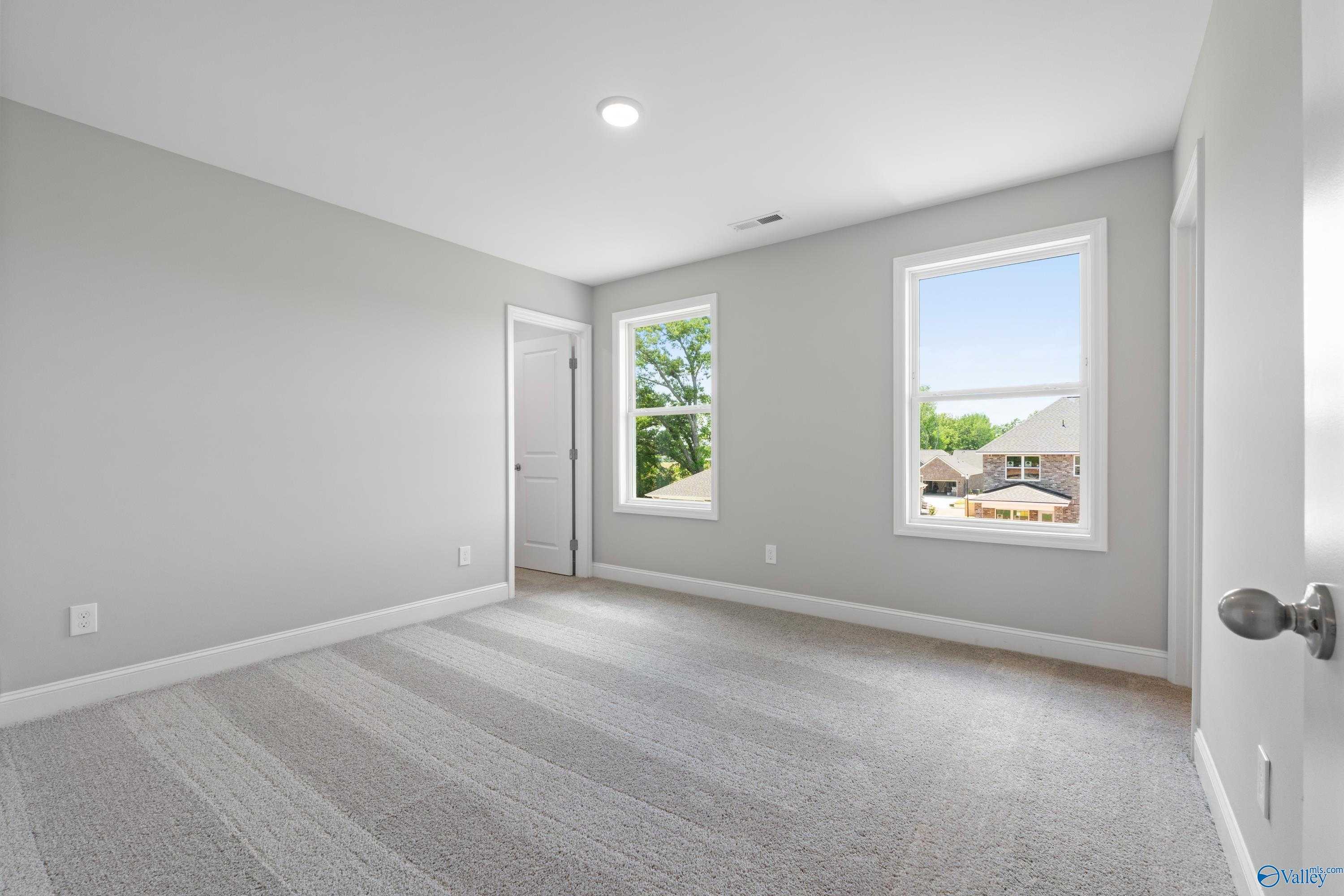 Bright secondary bedroom with gray walls, carpet flooring, and large windows in Davidson Homes The Chelsea B, New Market, AL