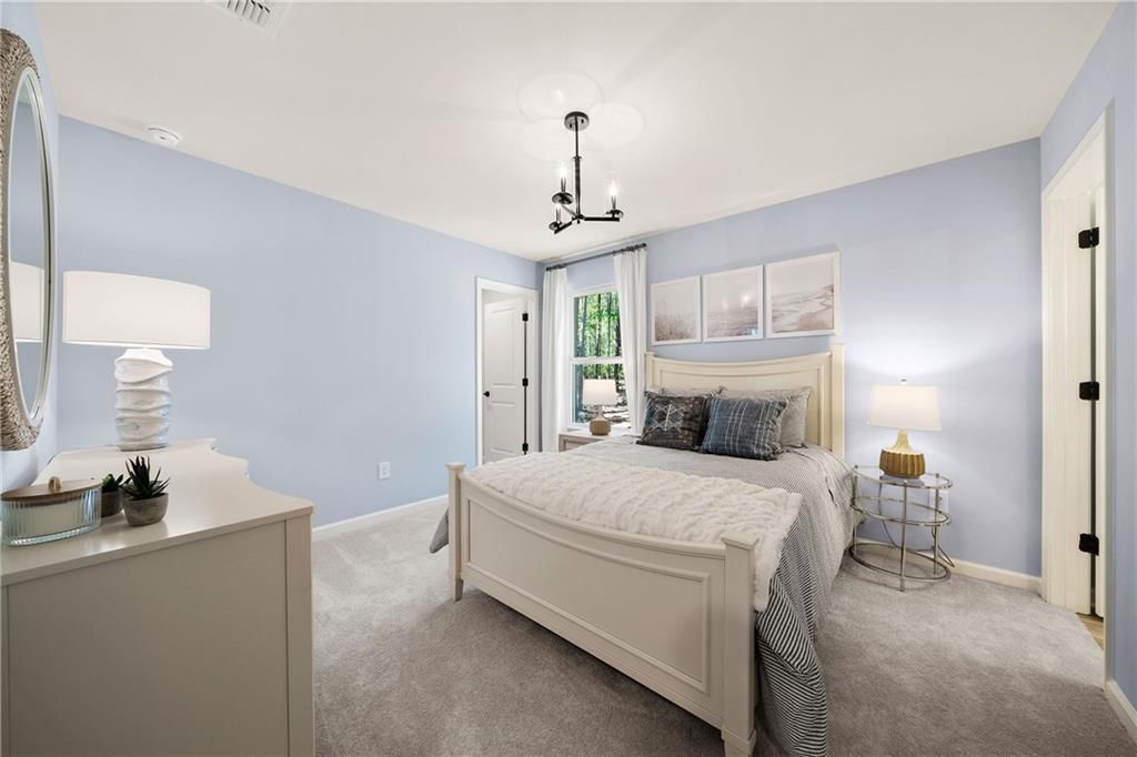 Serene blue bedroom with white king bed, gray carpet, lamps, and dresser in Davidson Homes Willow B, Dallas, Georgia