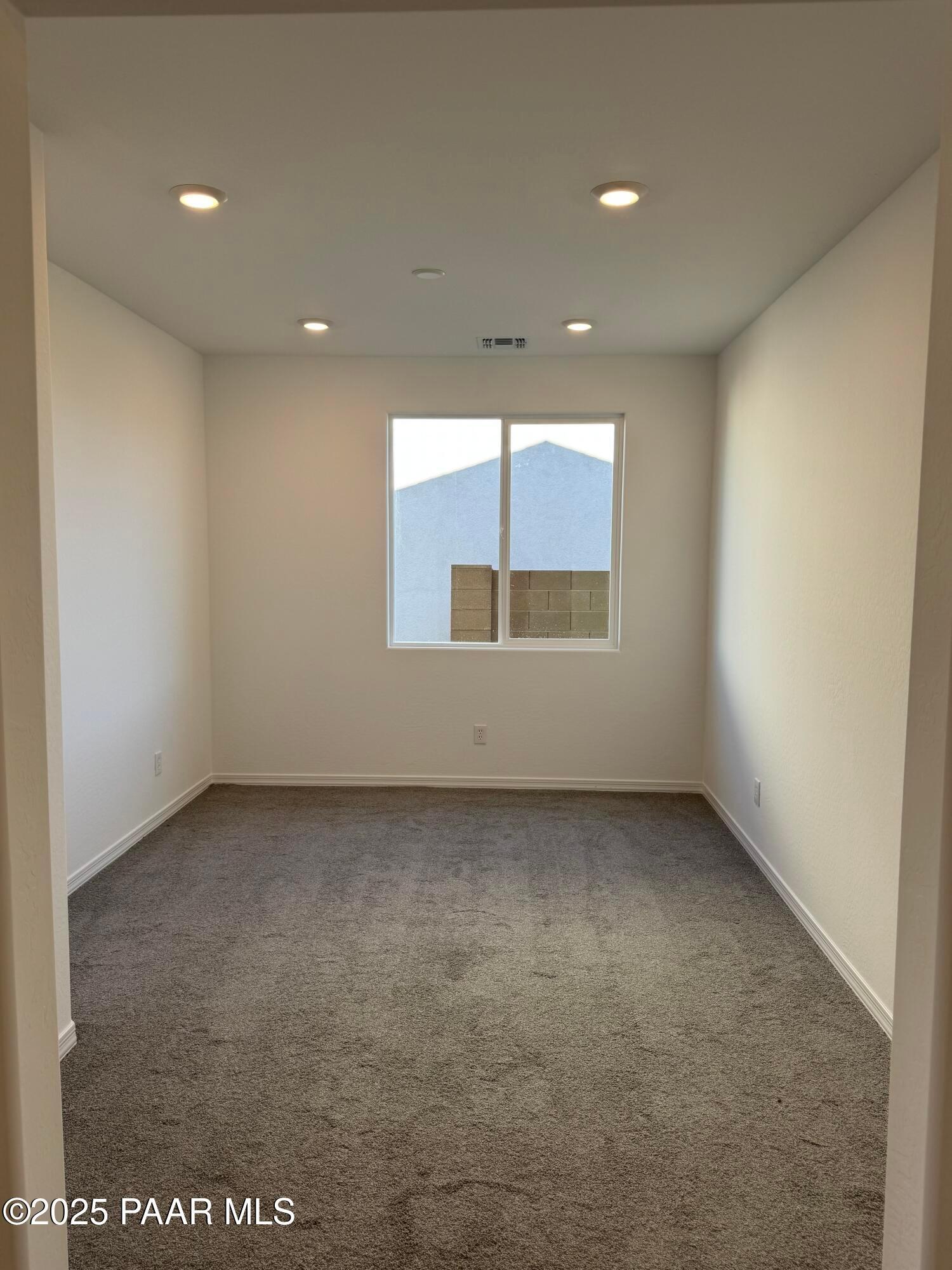 Empty bedroom with gray carpet, white walls, large window, and recessed lights in Davidson Homes Sunrise II A, Prescott, AZ
