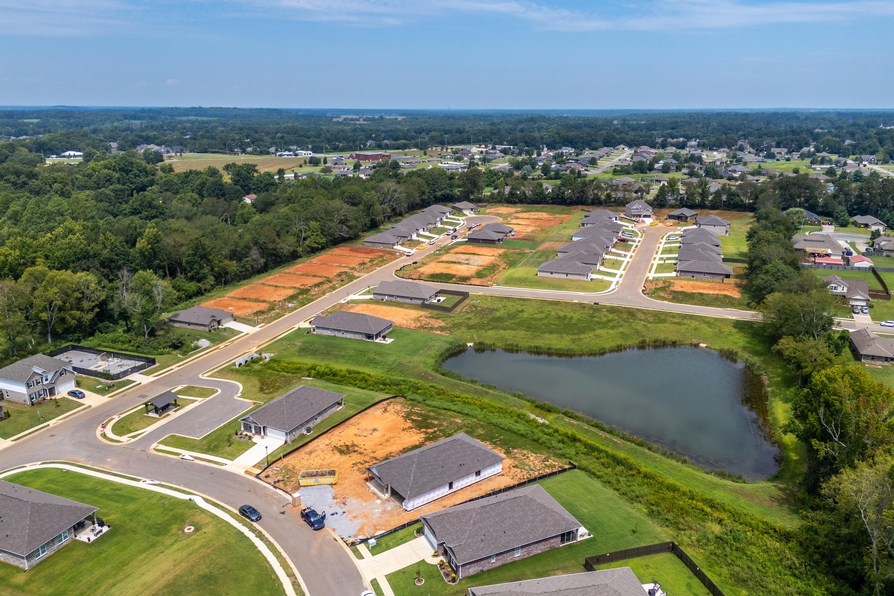 Aerial view of Flint Meadows neighborhood in New Market Alabama with new homes under construction, dirt roads, and heart-shaped pond