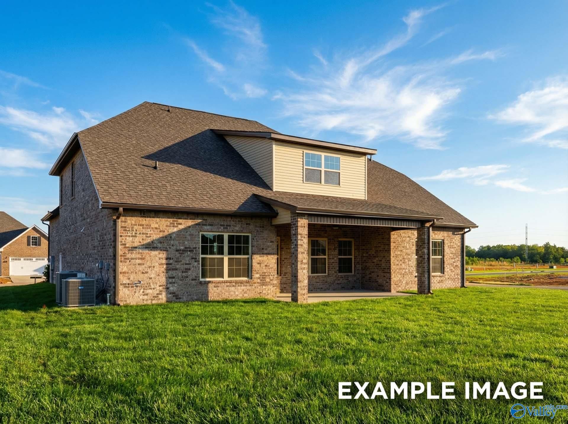 Two-story brick home with covered porch, dormer window, and green lawn under blue sky in Hollon Meadow, Decatur, Alabama - Davidson Homes The Emory