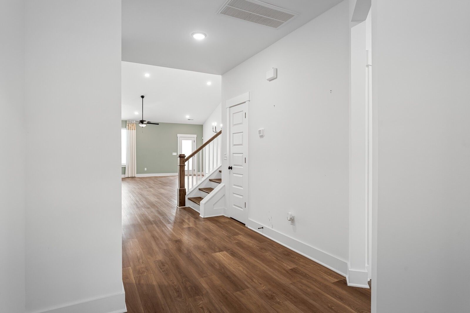 Bright foyer with hardwood floors, white walls, and curved oak staircase in Davidson Homes The Ridgeport, Gallatin, TN