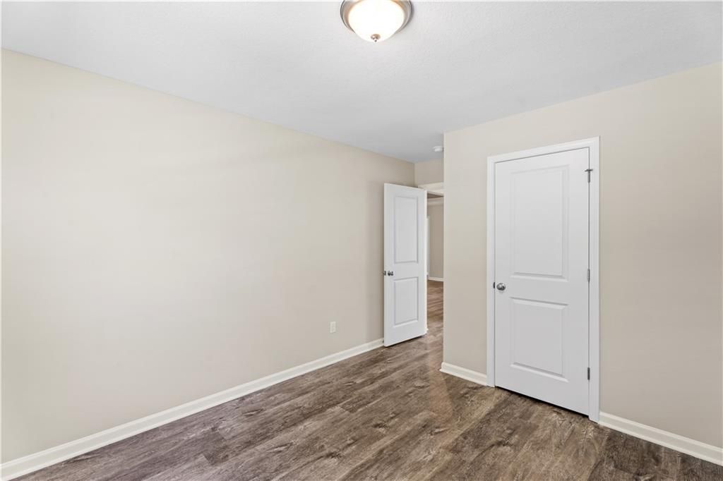 Bright secondary bedroom with beige walls, hardwood floors, and adjacent doorways in Davidson Homes The Washington, Phenix City