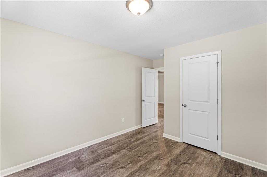 Bright secondary bedroom with beige walls, hardwood floors, and adjacent doorways in Davidson Homes The Washington, Phenix City